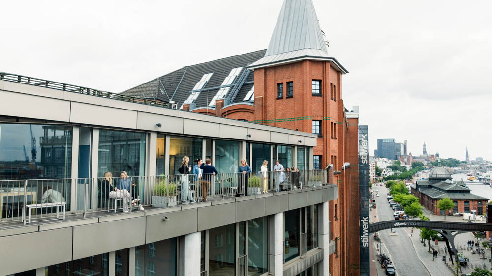 Außenansicht Hamburg: moderne Seminarräume mit Balkon, Teilnehmer:innen im Austausch