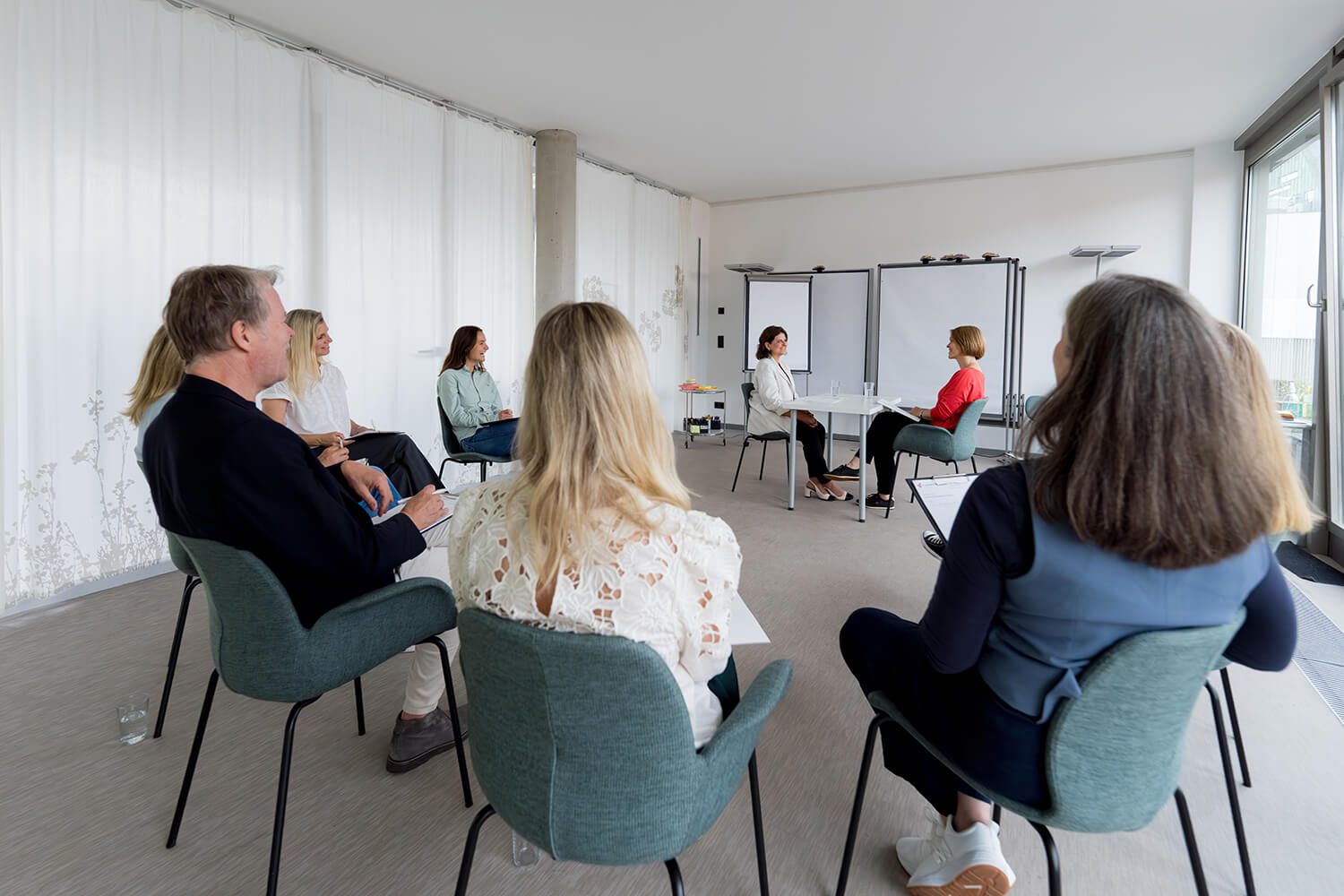 Beratung: Systemische Organisationsentwicklung & Teamcoaching Coaching-Ausbildung – Trainer präsentiert am Bildschirm vor Teilnehmenden im Seminarraum