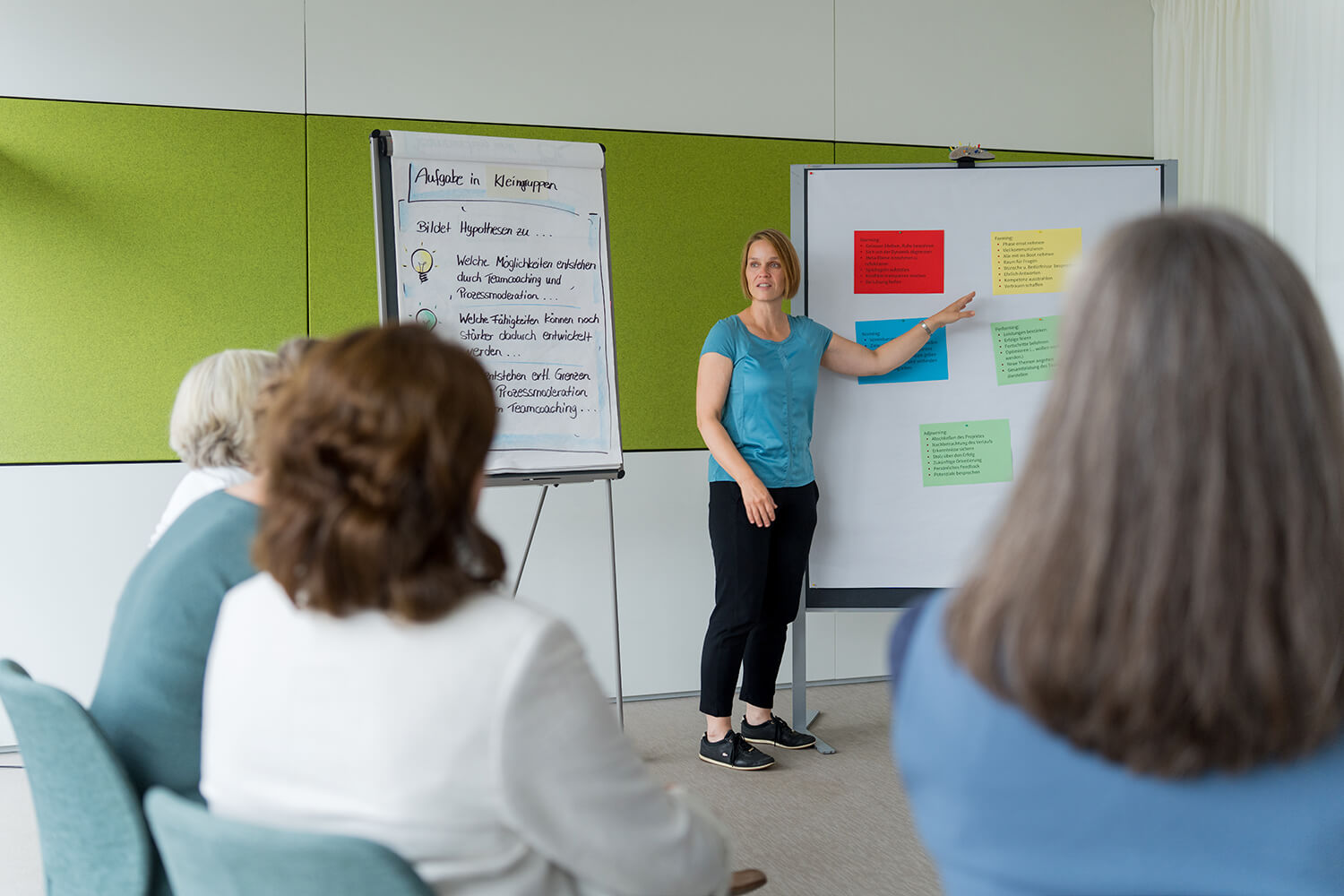 Drei Teilnehmende stehen auf farbigem Persönlichkeitsrad (Lumina) im Seminarraum