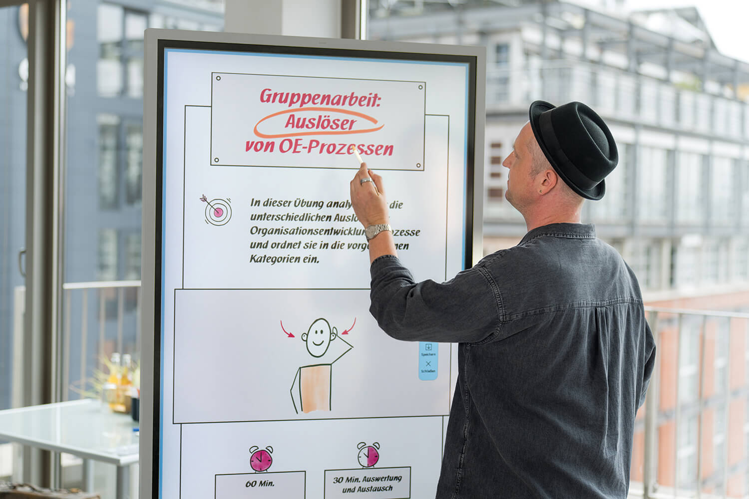 Trainer präsentiert an digitalem Whiteboard – Ausbildungsgruppe folgt der Erklärung im Seminarraum