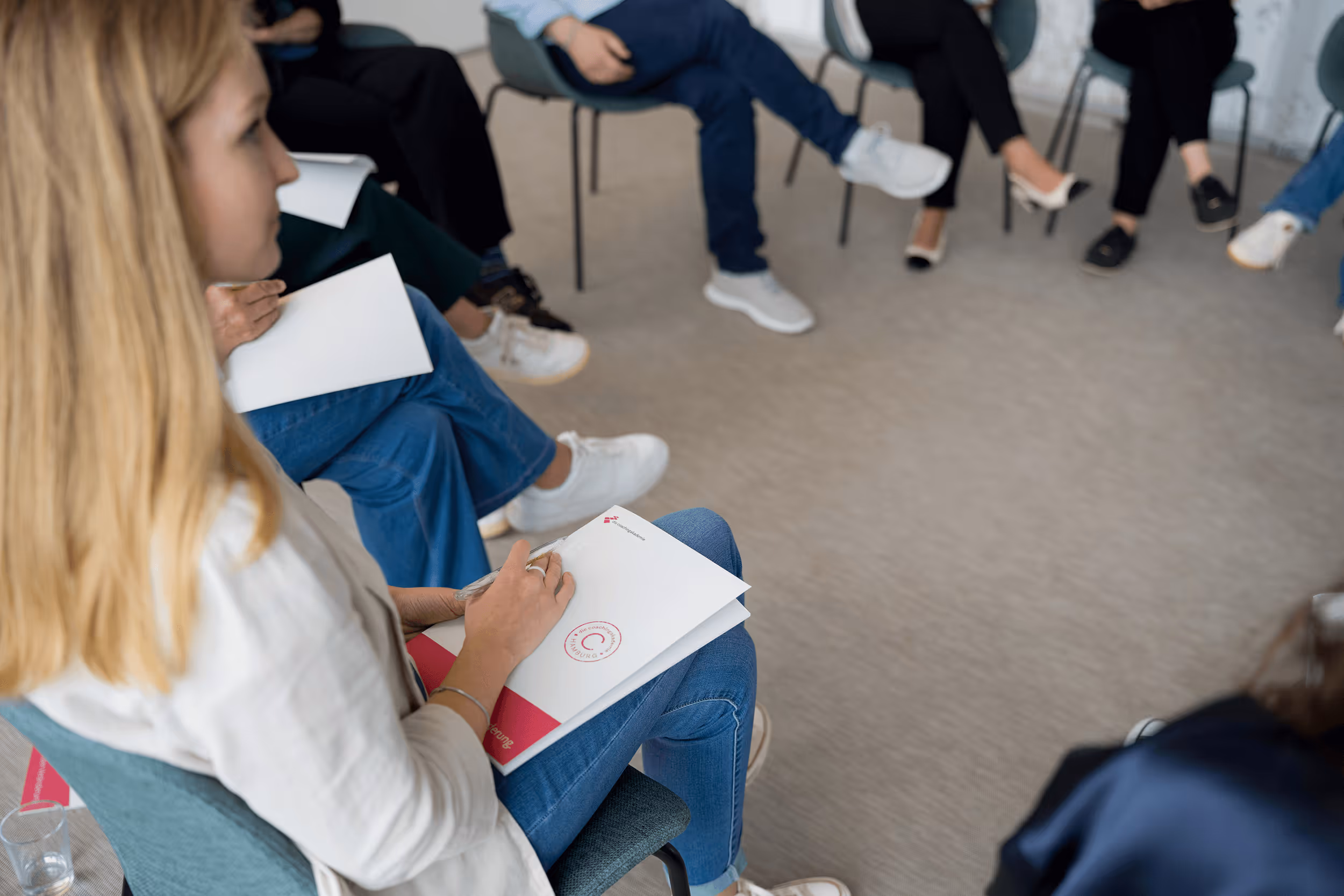 Weiterbildung – Gruppe im Stuhlkreis im Seminarraum, Gesprächssituation; Blick durch Glasfront mit Spiegelung