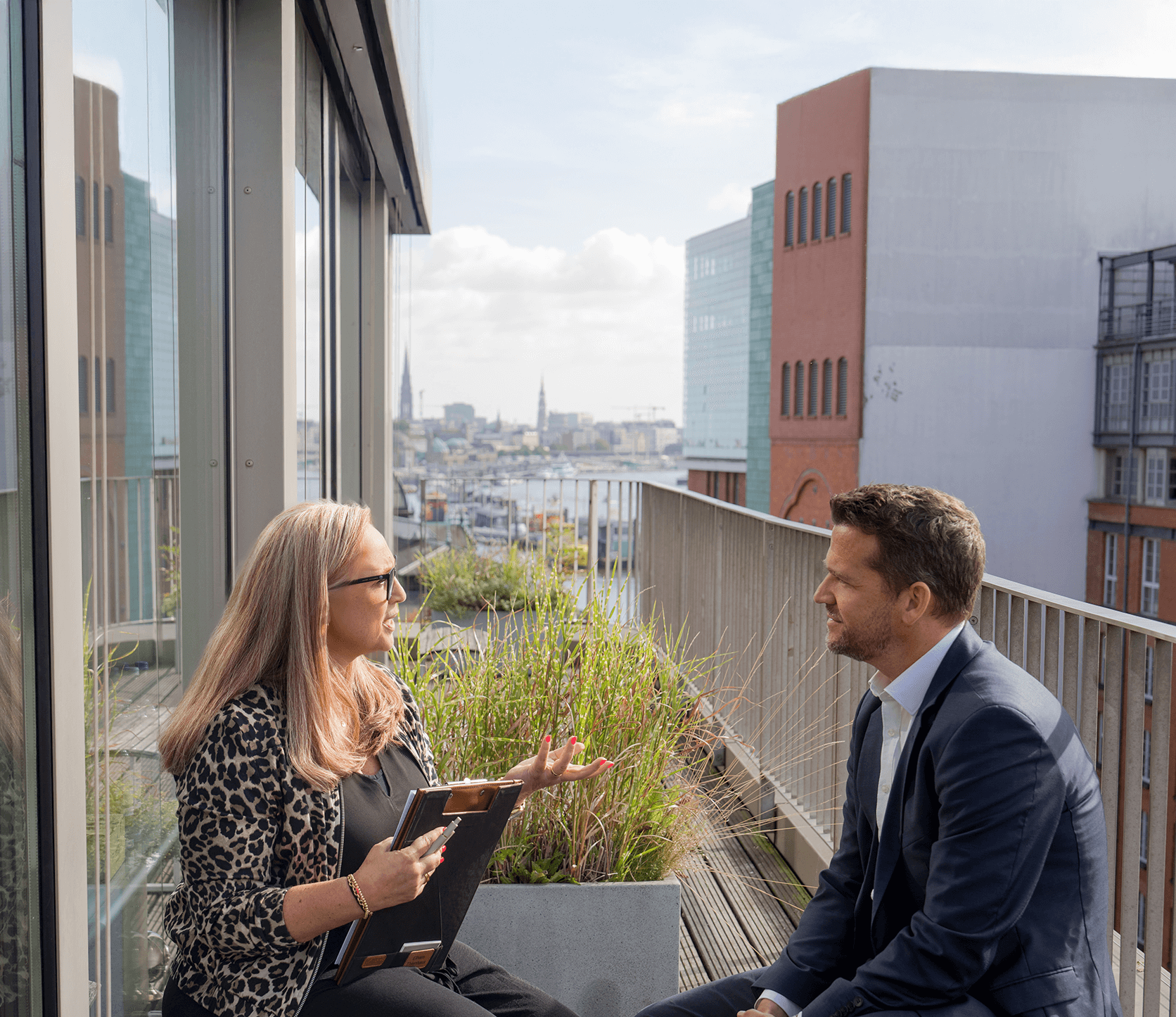 Beratung – Gespräch am Tisch mit zwei Ansprechpersonen, Blick durch Glas