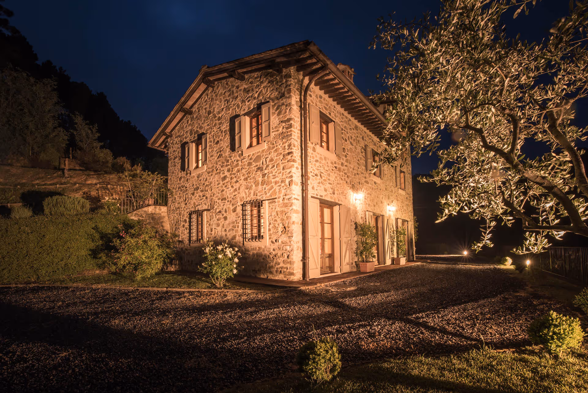 Farmhouse at night with warm lighting and Tuscan stone facade