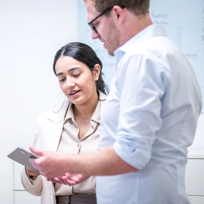 Zwei Teammitglieder arbeiten partnerschaftlich an ihren Schreibtischen zusammen.