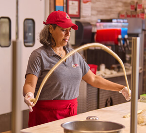 A baker rolling & twisting pretzel dough