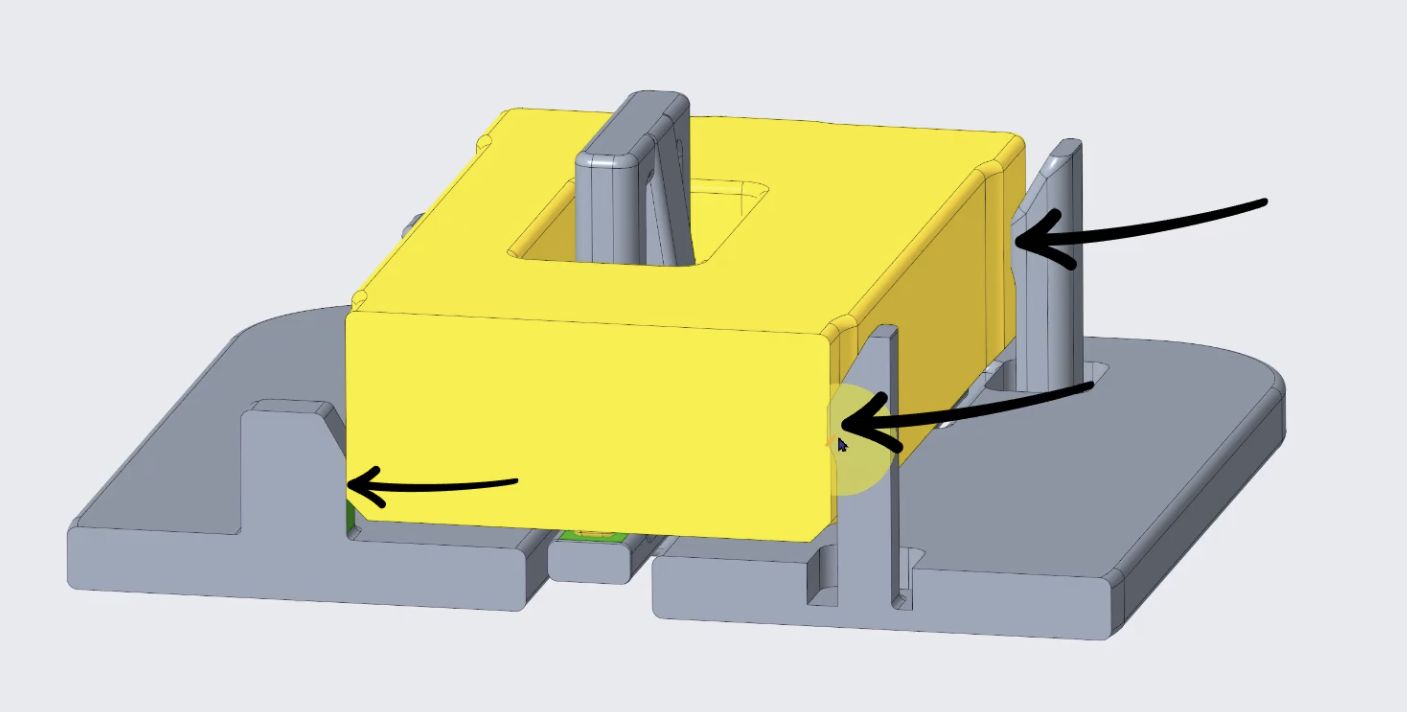 3D model of a yellow rectangular component mounted on a gray base with three black arrows pointing to specific connection points between the yellow and gray parts.