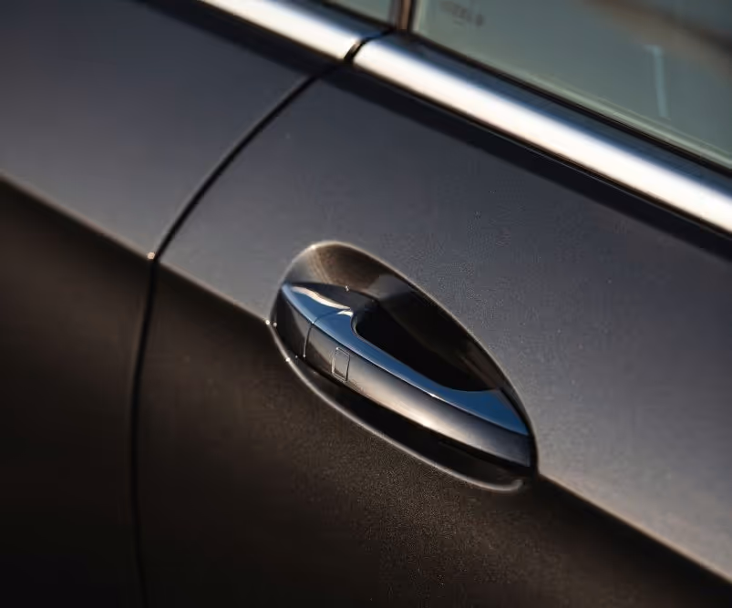 Close-up of a sleek black car door handle with silver trim.