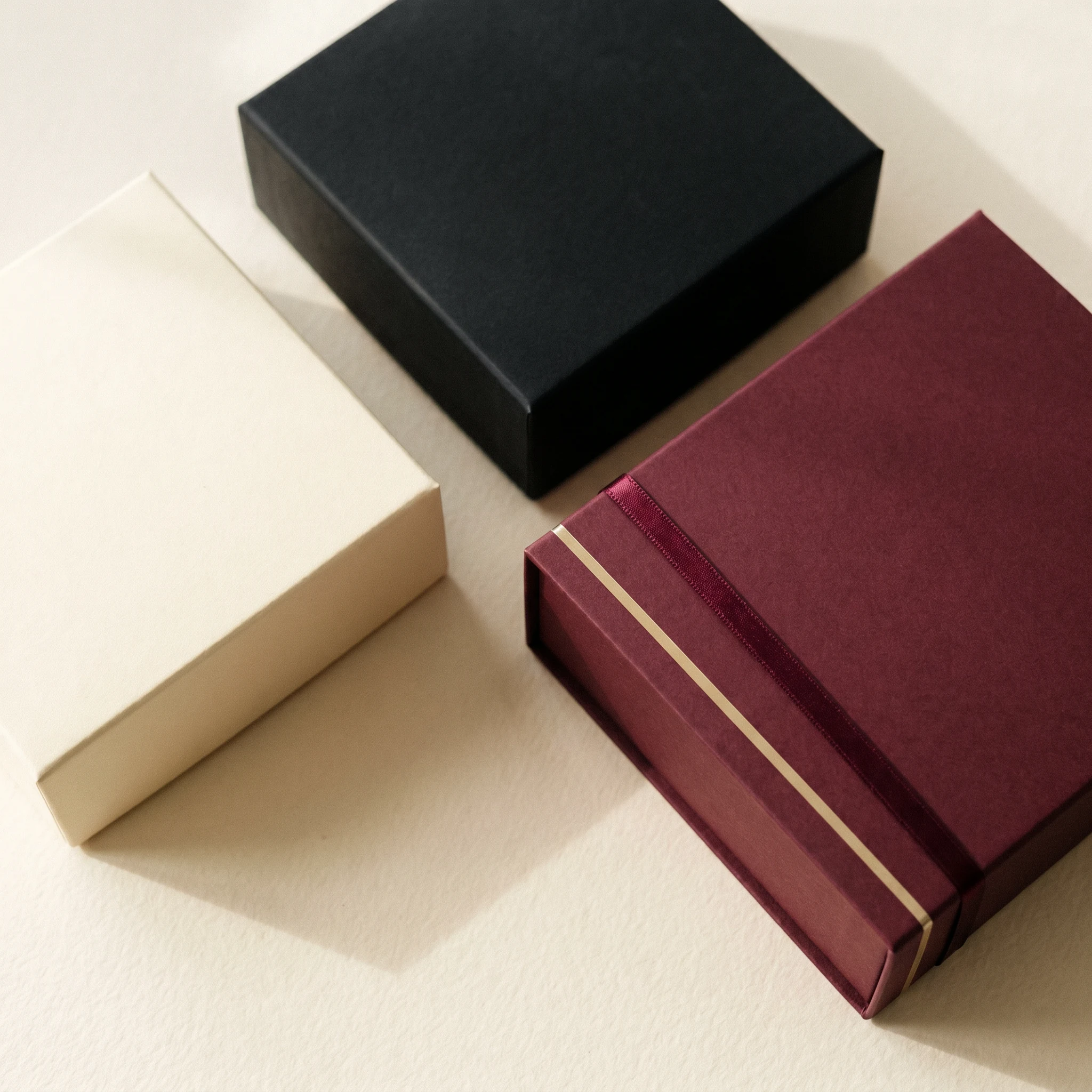 Verpackungsdesign — Drei minimale Premium-Boxen top-down auf Cream-Surface.