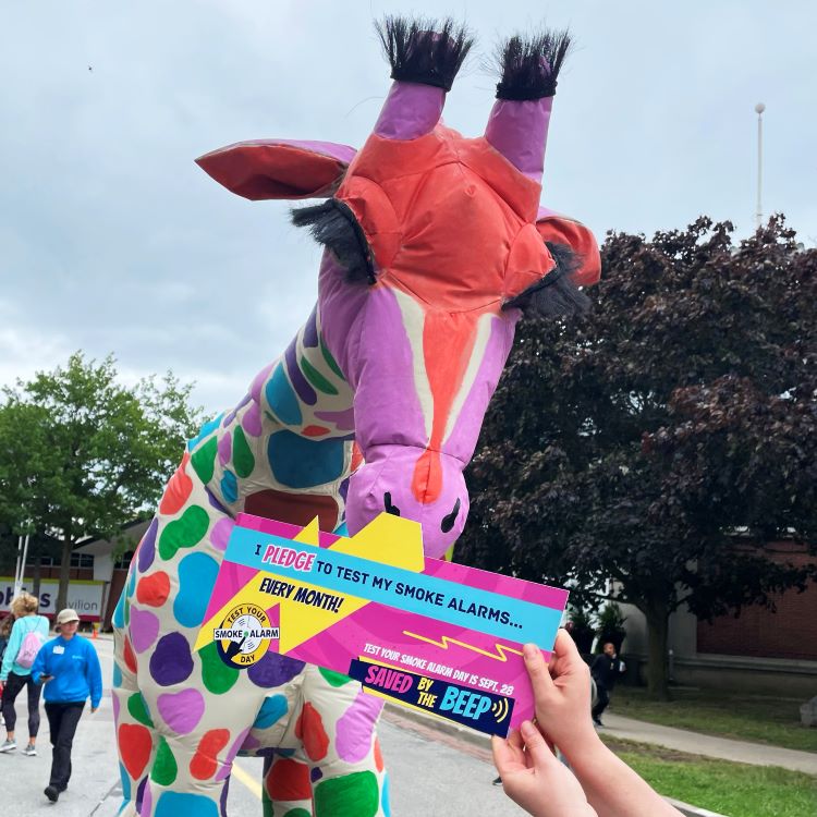 Image of CNE mascot with a sign pledging to test their smoke alarms.