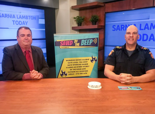 image of fire service members promoting Test Your Smoke Alarm Day at a news station.