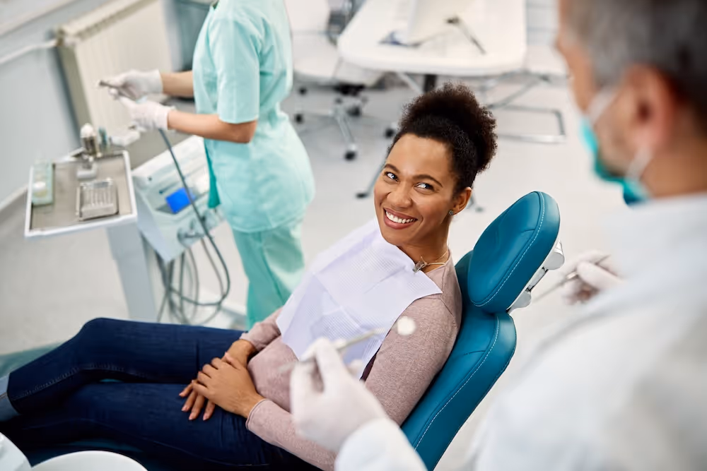 A woman sitting in a dentist chair smiling.