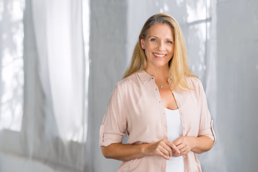 A woman standing in front of a window smiling.