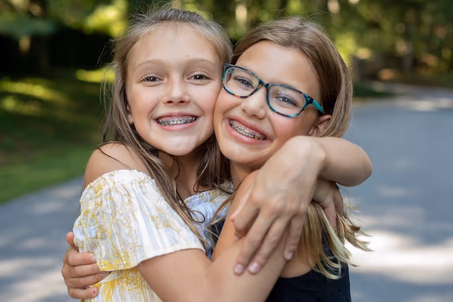 Two young girls hugging each other on a street.
