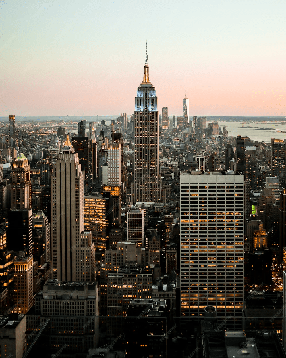 Aerial view of New York City at sunset with the Empire State Building centered in the skyline.