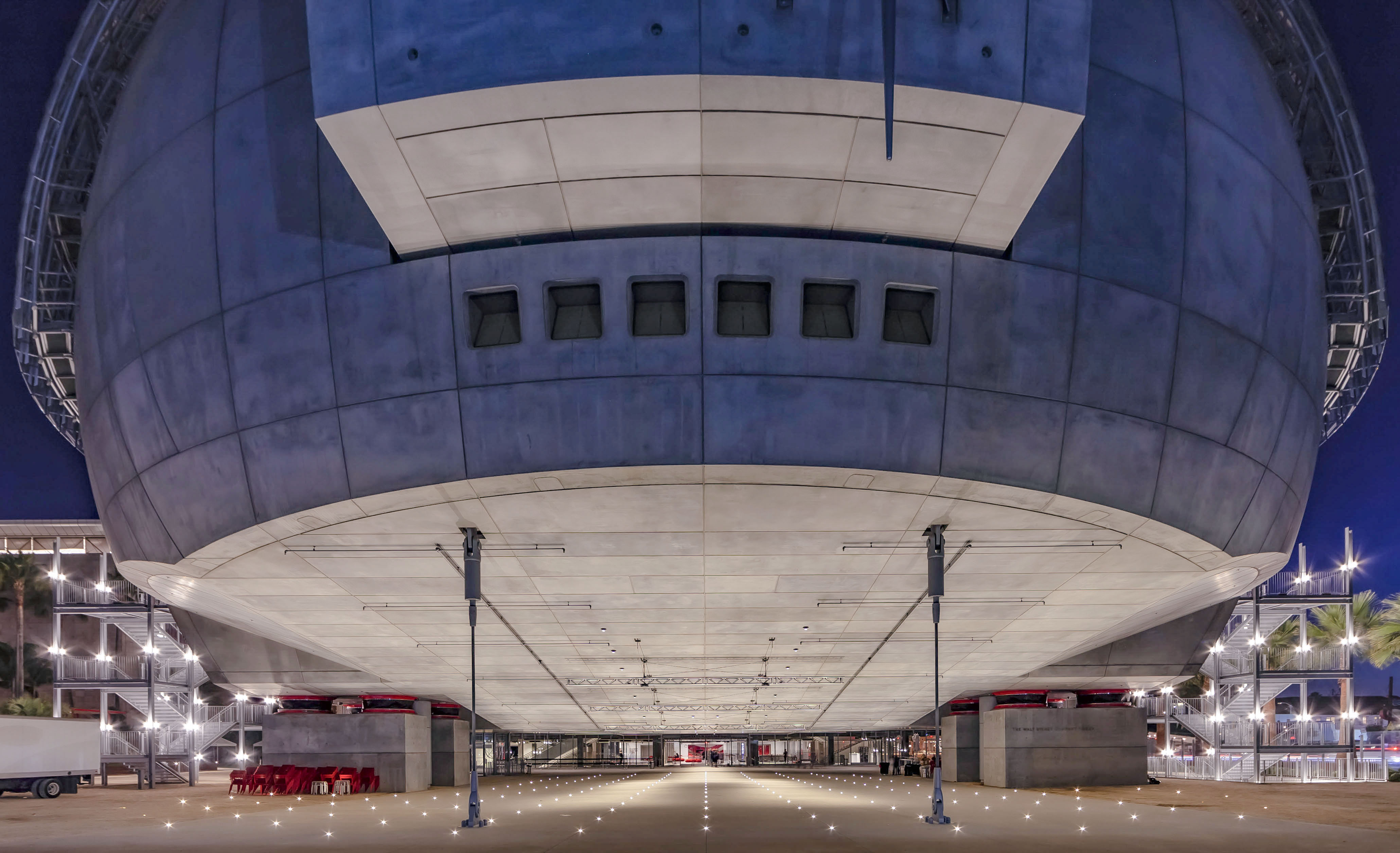 Dramatic upward view of the spherical structure of the Academy Museum of Motion Pictures at night, with illuminated pathways and modern architectural lines.