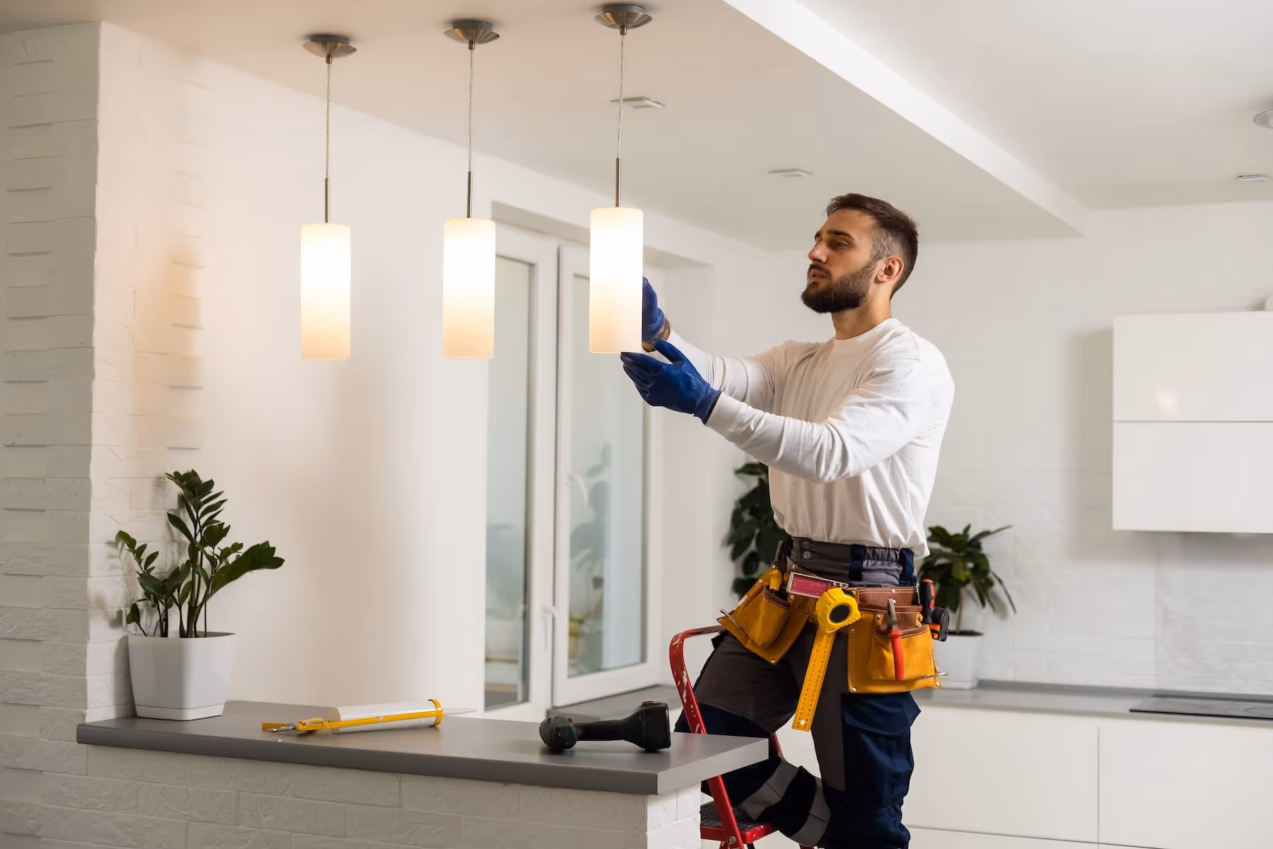 Electrician installing light bulbs in a pendant light.