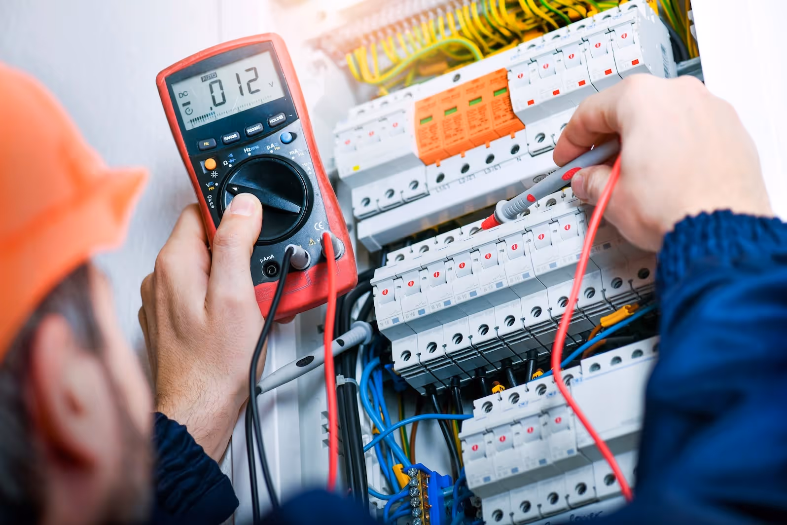 Electrician using a voltage tester on a breaker panel.