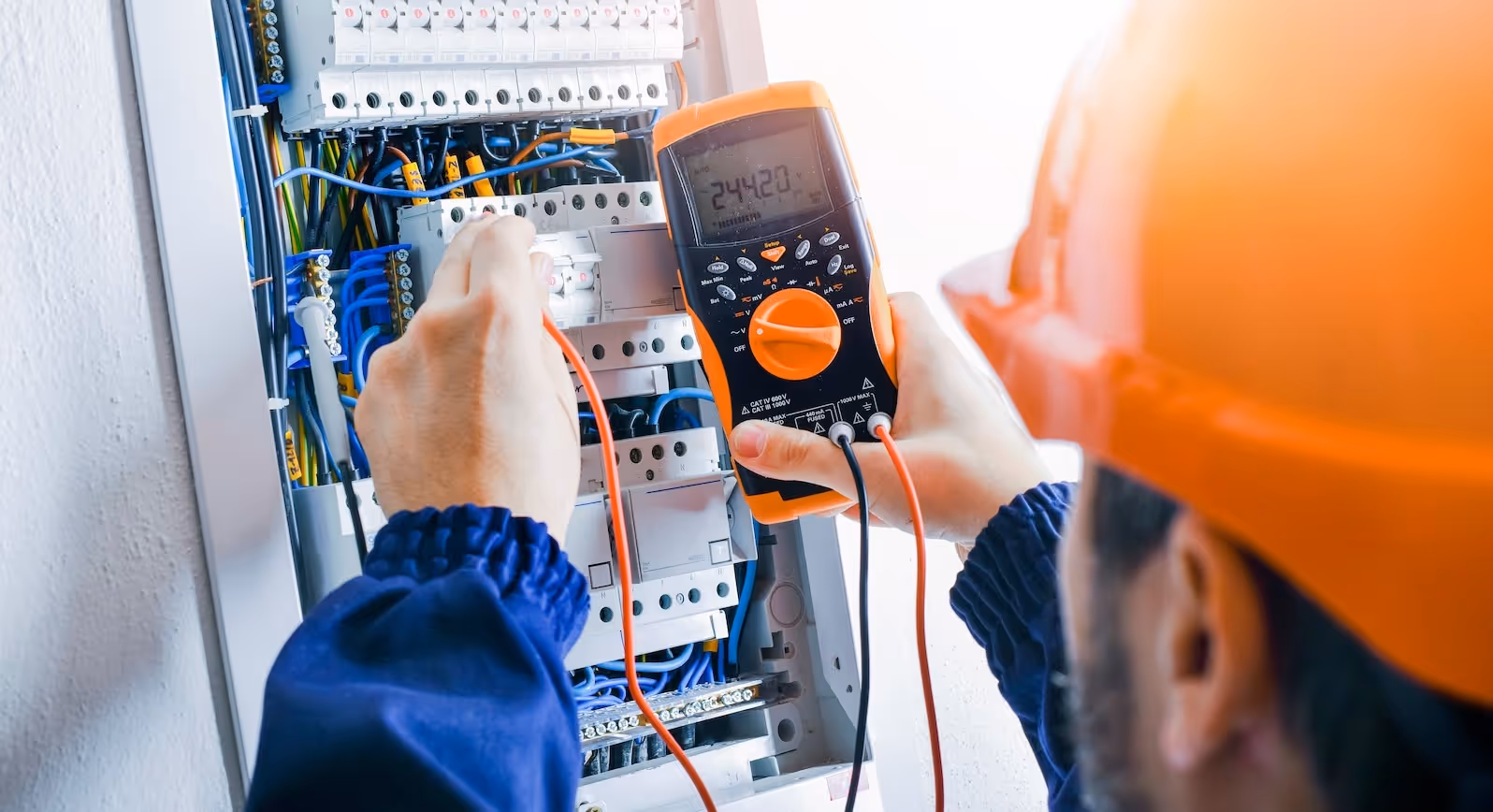 Electrician using a voltage tester on a breaker panel.