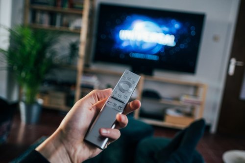 a person's hand pointing a remote at a smart TV