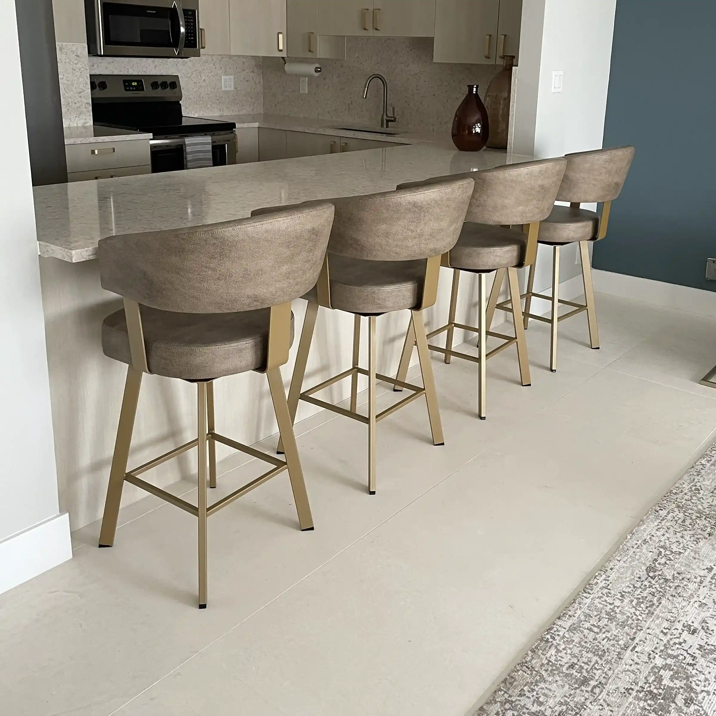 Four brown leather bar stools with gold-toned legs sit at a white kitchen counter
