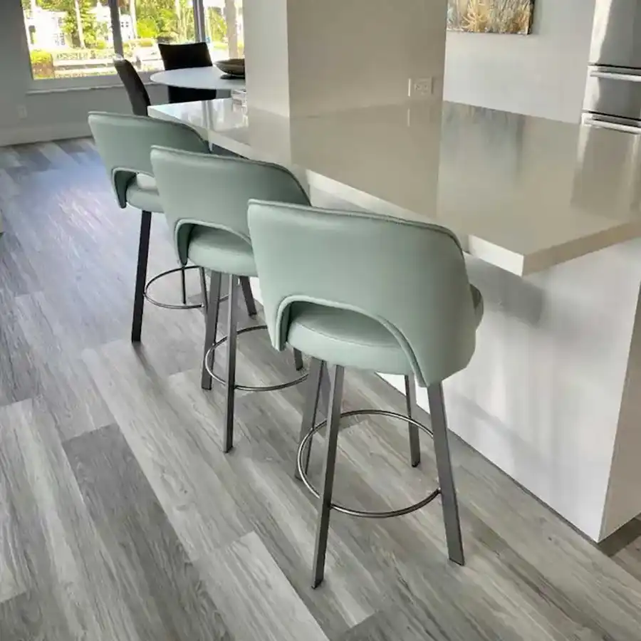 Three mint green bar stools with black legs at a white kitchen counter.