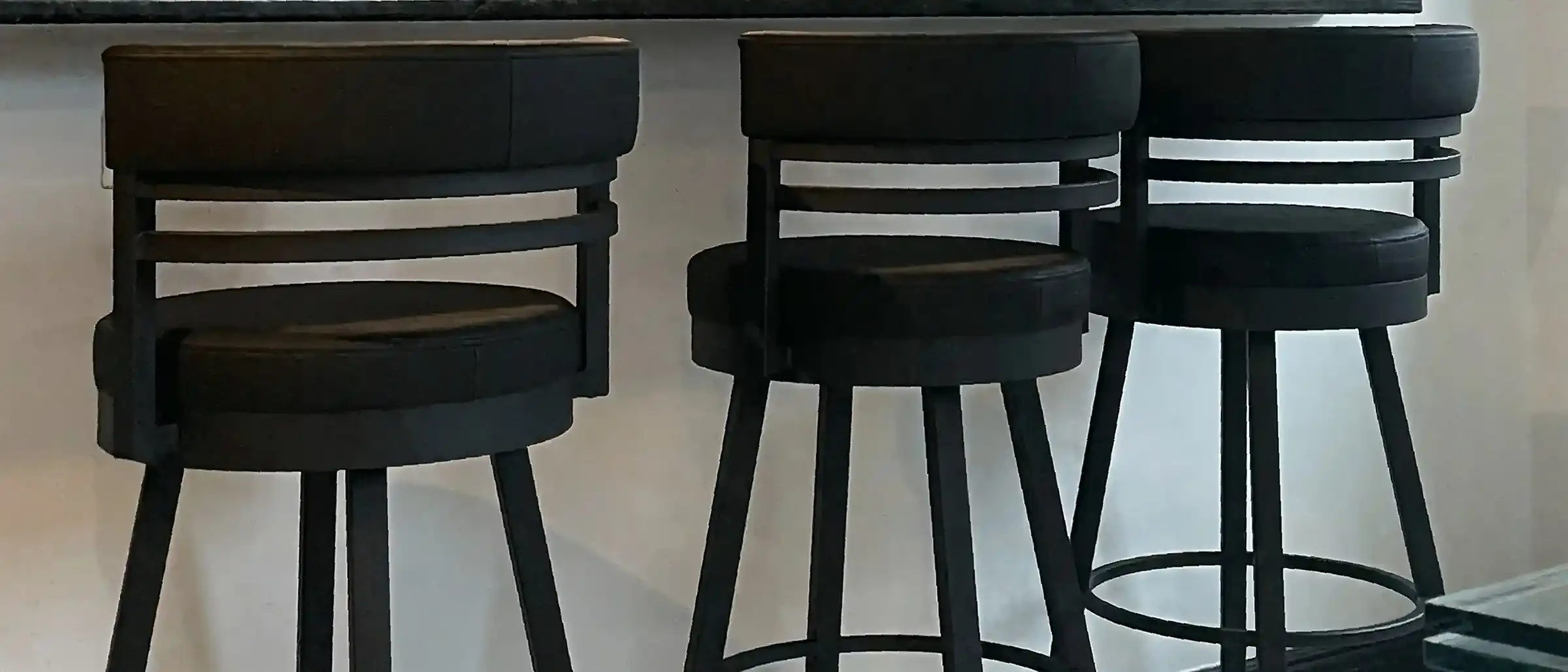 Three Amisco Render 30" swivel bar stools in black metal finish with black upholstered seats, modern industrial design, perfect for kitchen islands or home bars.