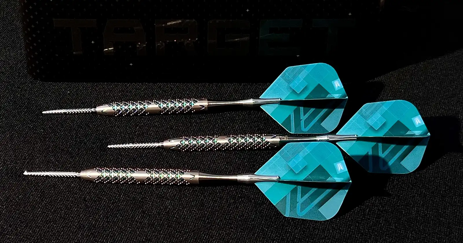 Target Darts "975" Swiss Point darts set, featuring unique pixel grip and interchangeable points. Steel tip darts with teal and silver design, displayed with Target logo.