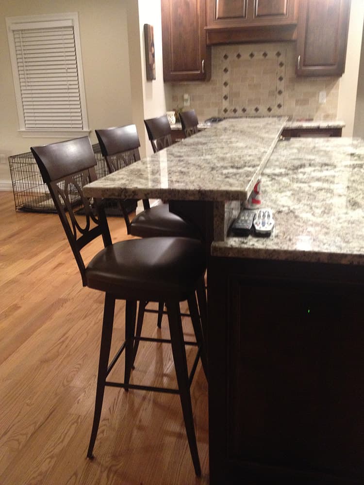 four black kitchen stools at a marble counter