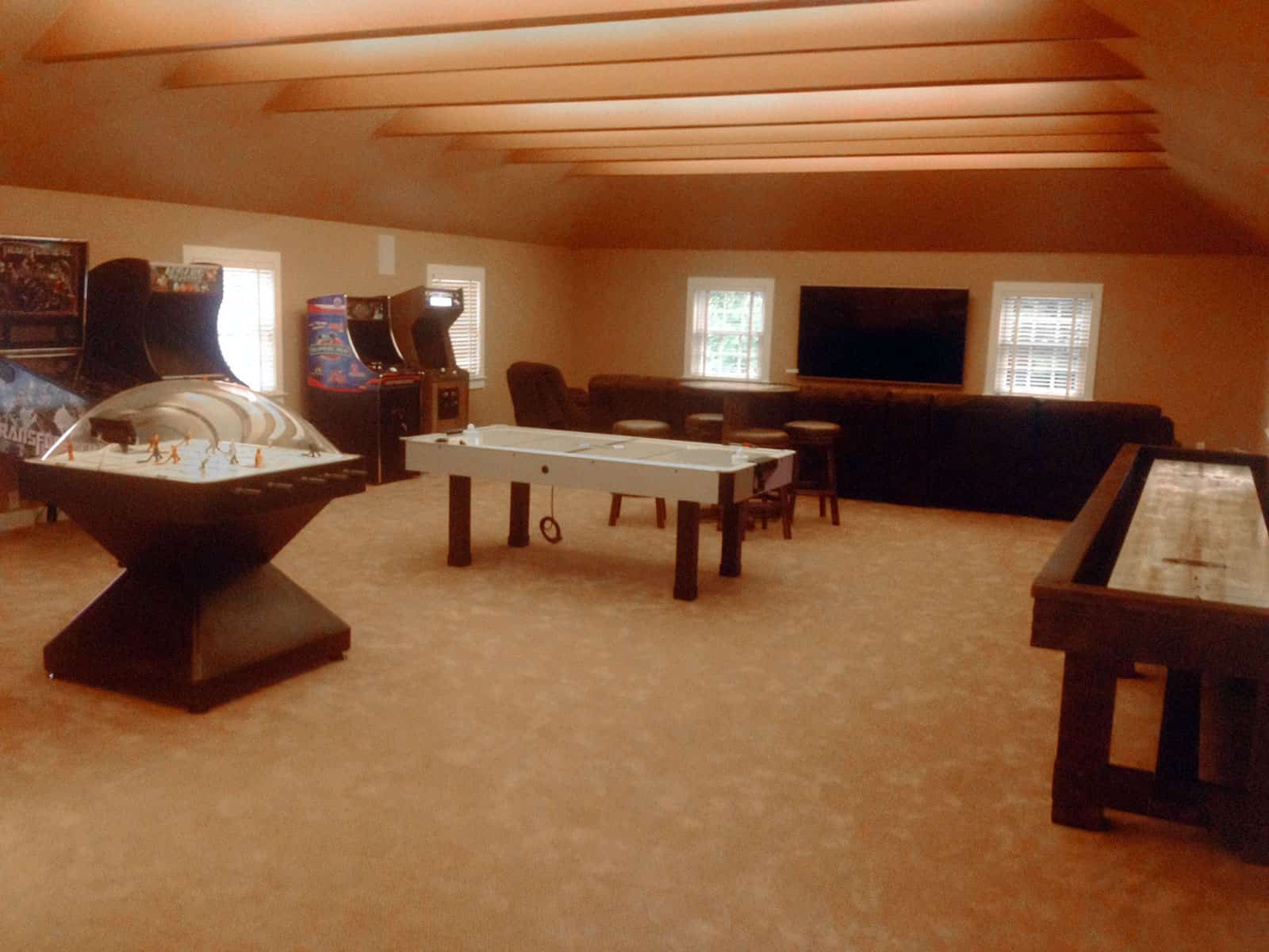 bubble hockey, shuffleboard, air hockey, three arcade game in a game room