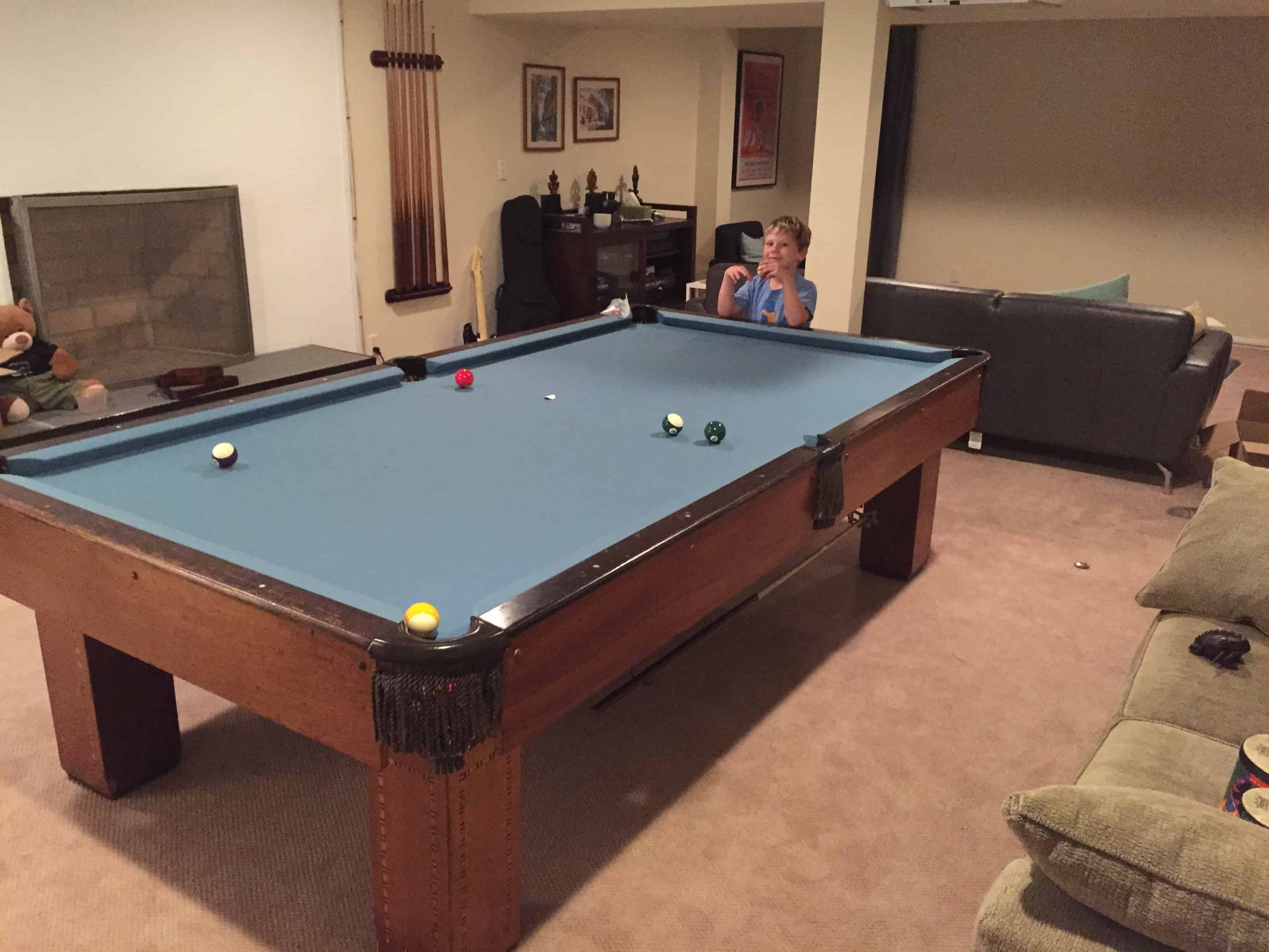 green pool table with a cue rack