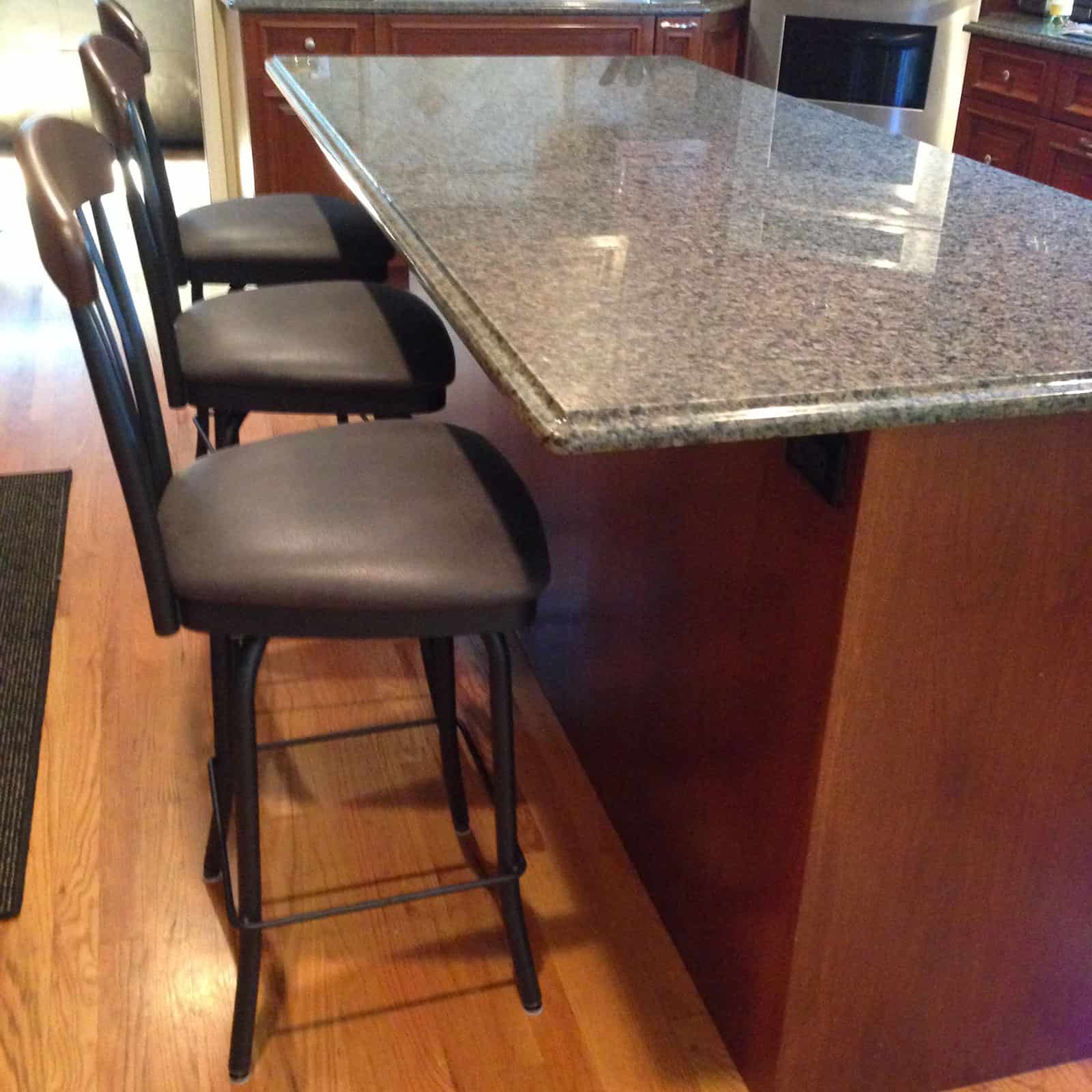 three black kitchen stools at a marble counter