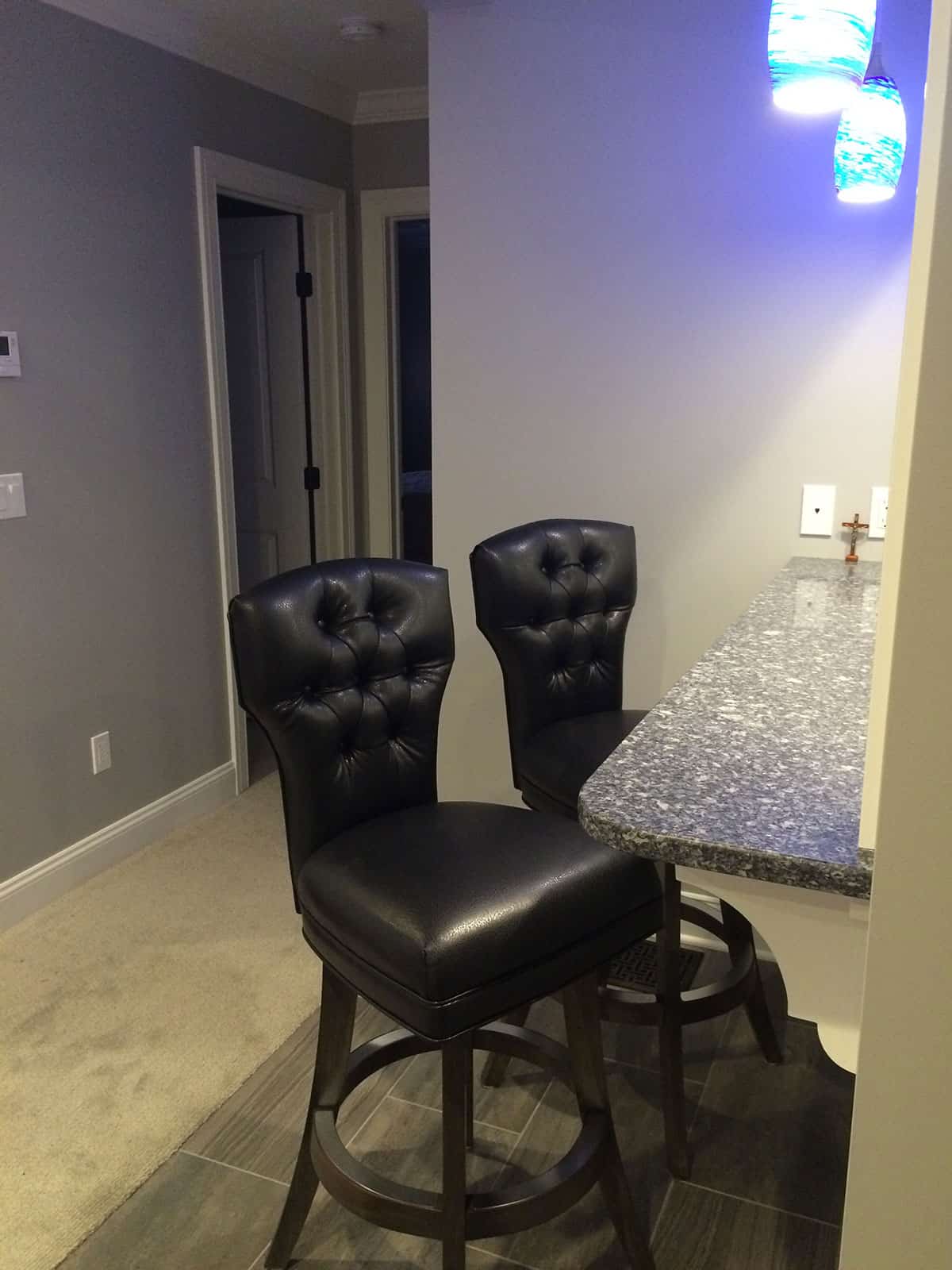 two black kitchn stools at a marble counter