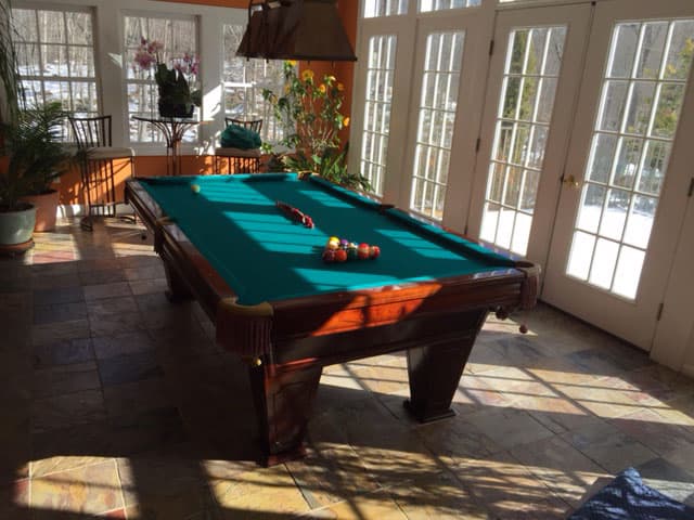 green pool table with billiard lighting on a porch