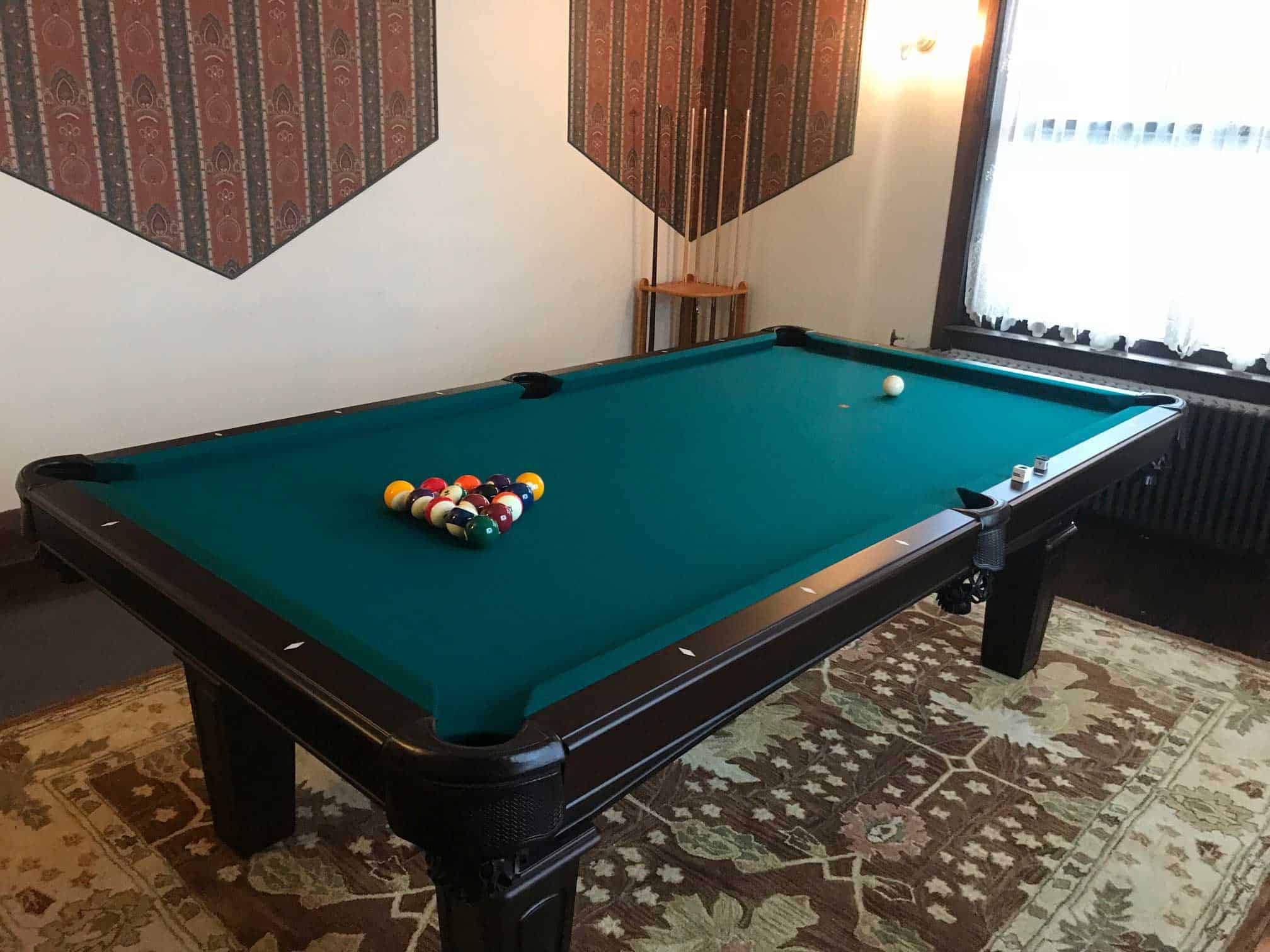 green pool table with a cue rack