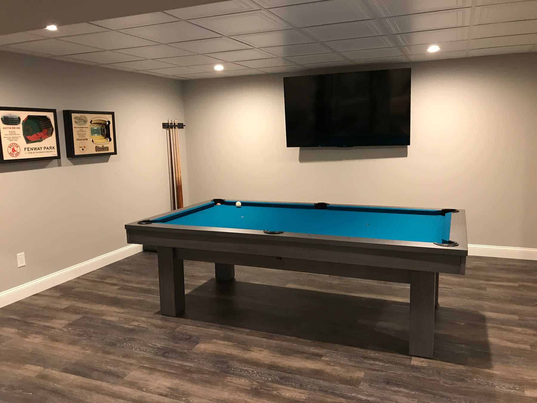 green pool table in a basement with a cue rack