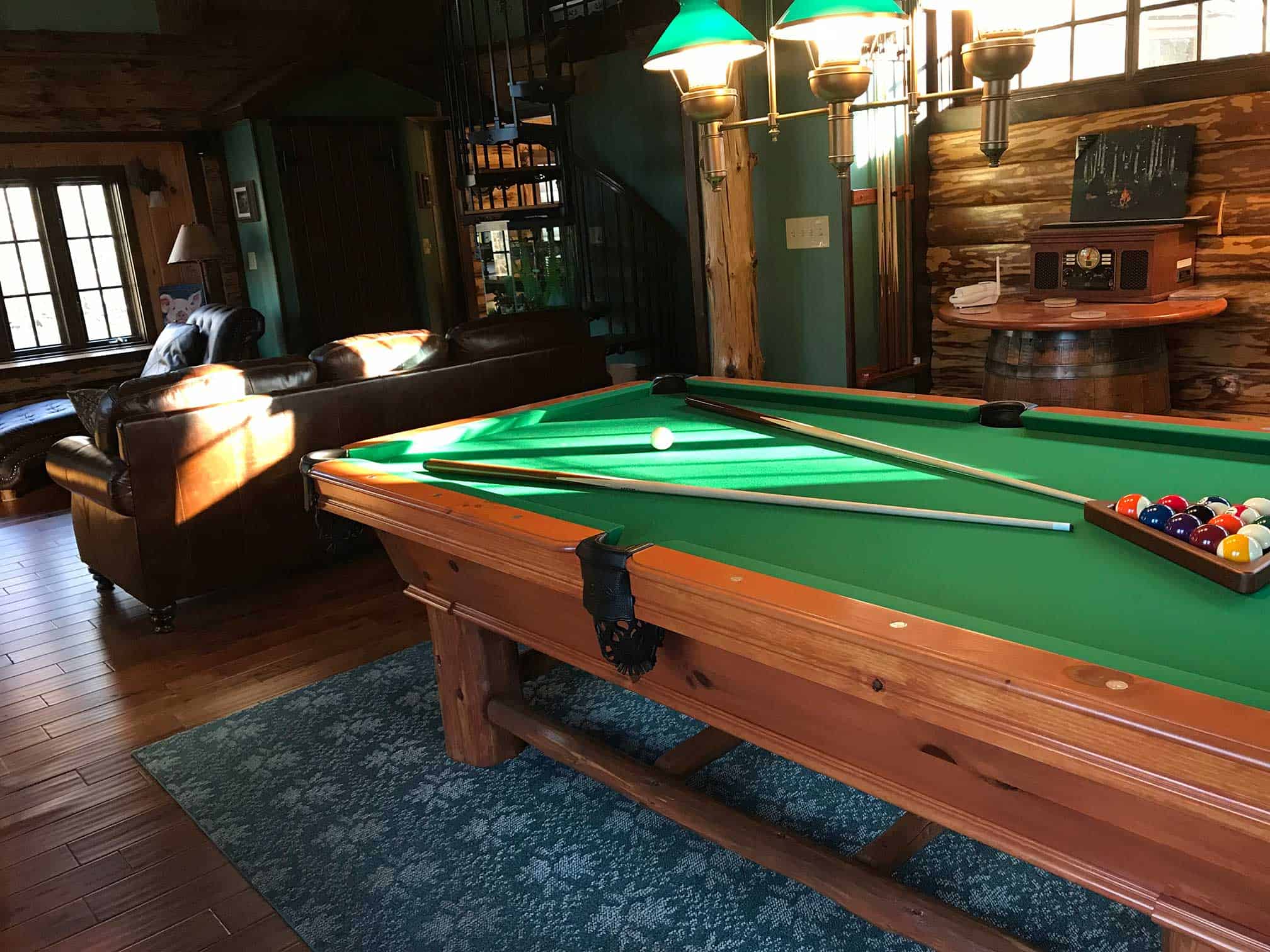 green pool table with overhead billiard lighting