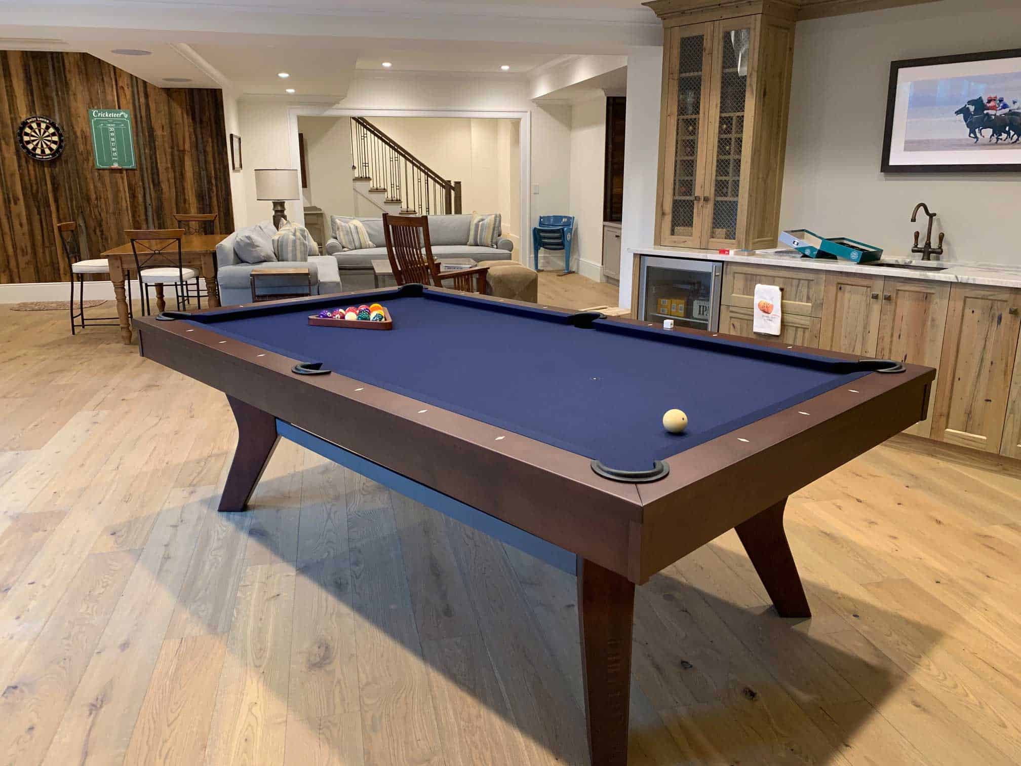 blue pool table in a game room with darts and a scoreboard