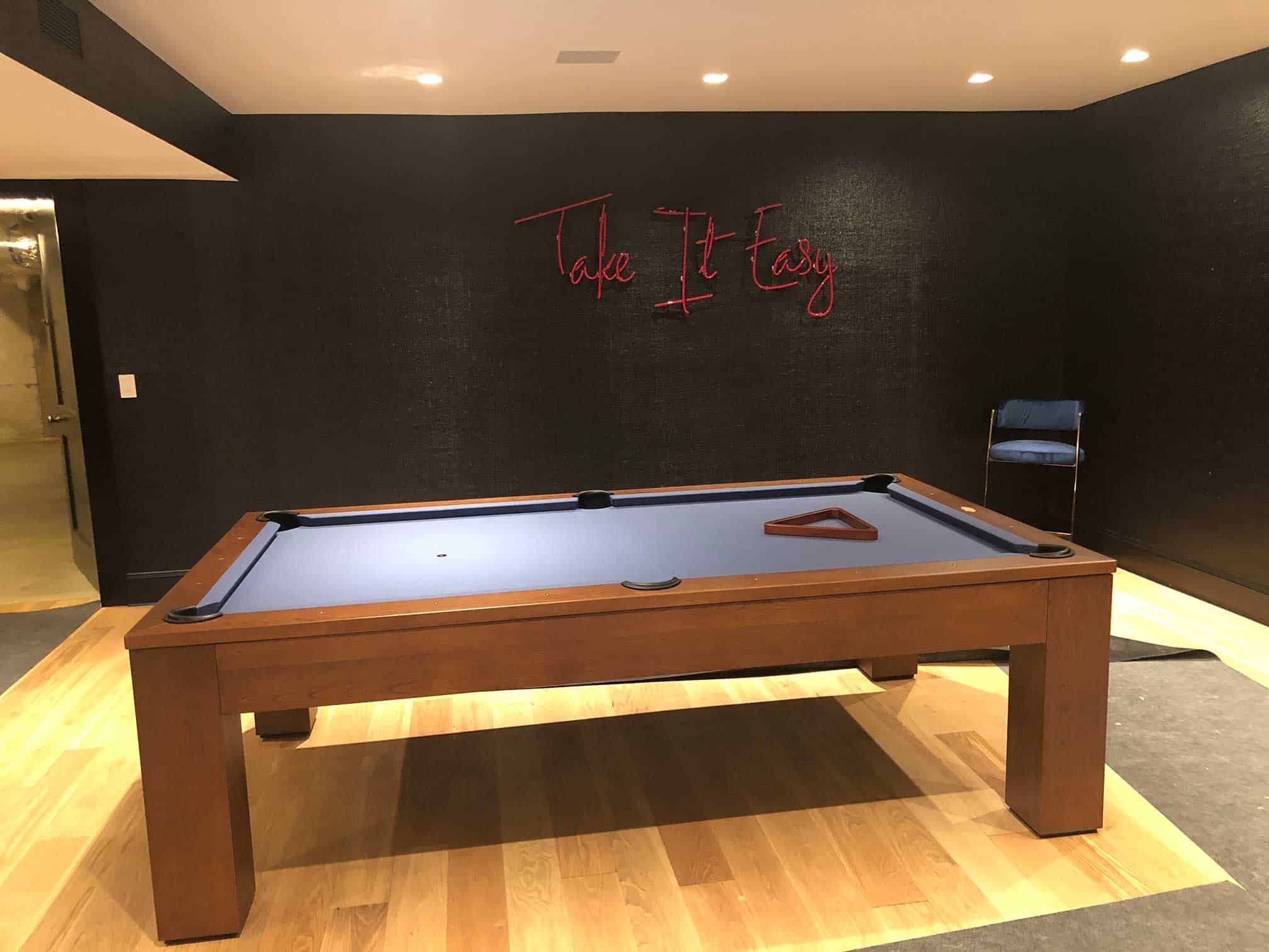 blue pool table with a Take It Easy sign on the wall