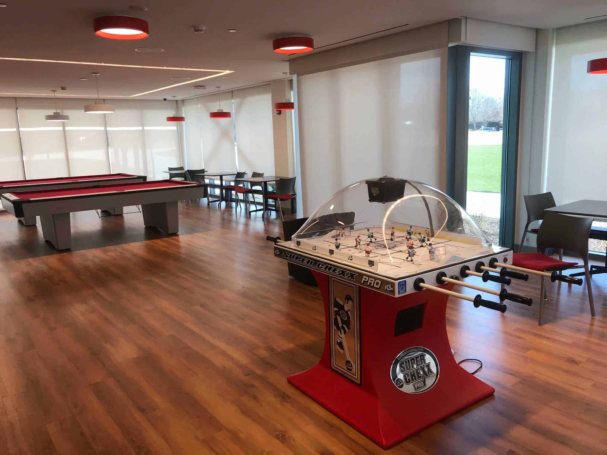 sacred heart game room with two red pool tables and super chexx bubble hockey
