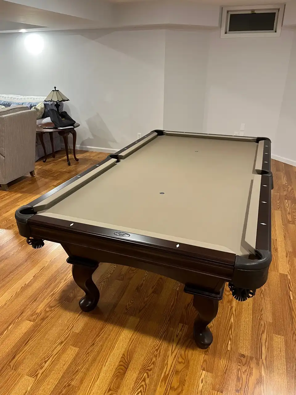 tan felt olhausen pool table on a hardwood floor
