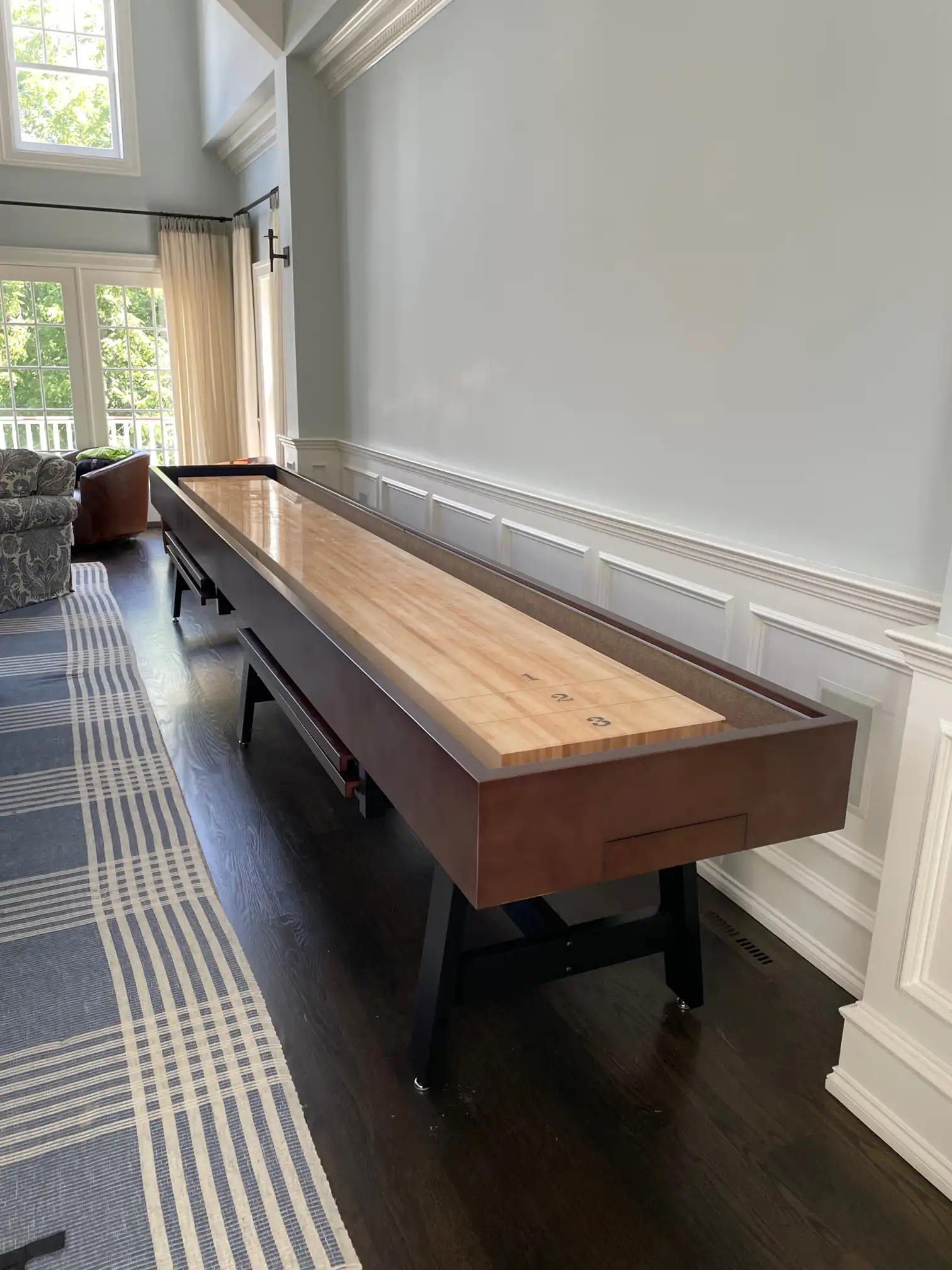 shuffleboard table on the side of the room next to a blue rug