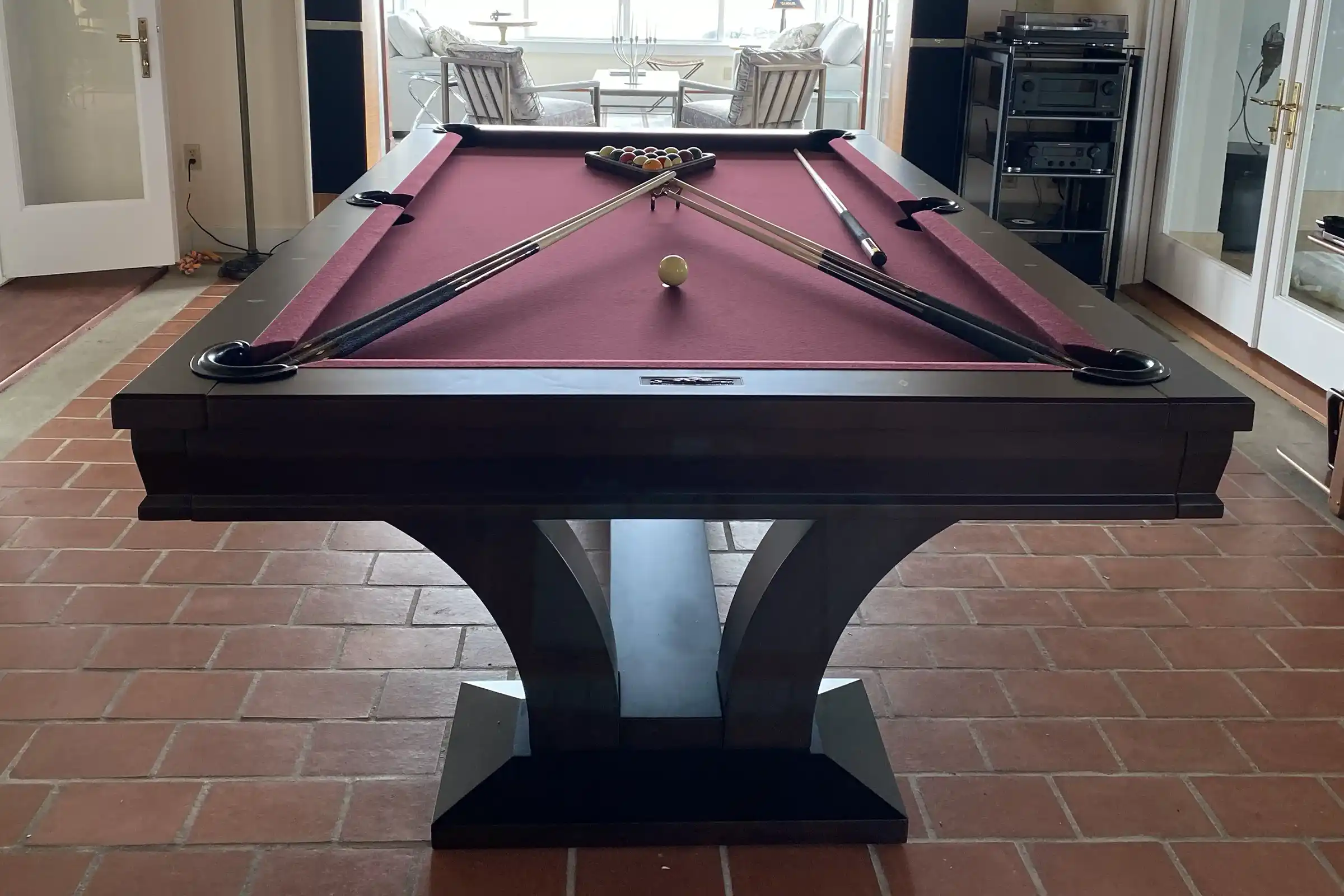 maroon felt pool table on a brown tile floor
