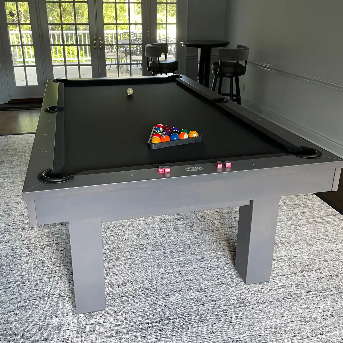 silver olhausen pool table with black cloth on a white rug