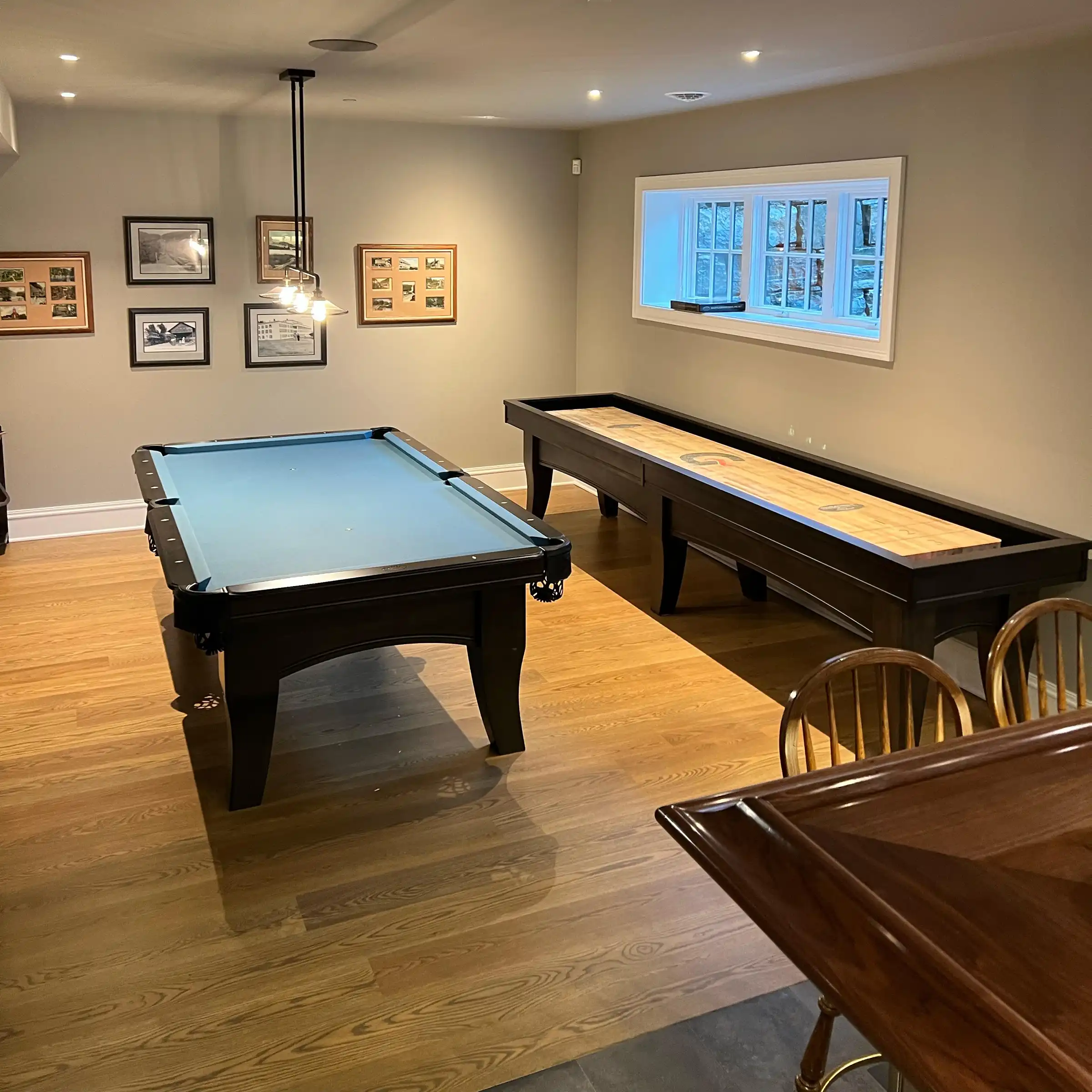 game room next to a bar with a greenish blue pool table and a full length shuffleboard 