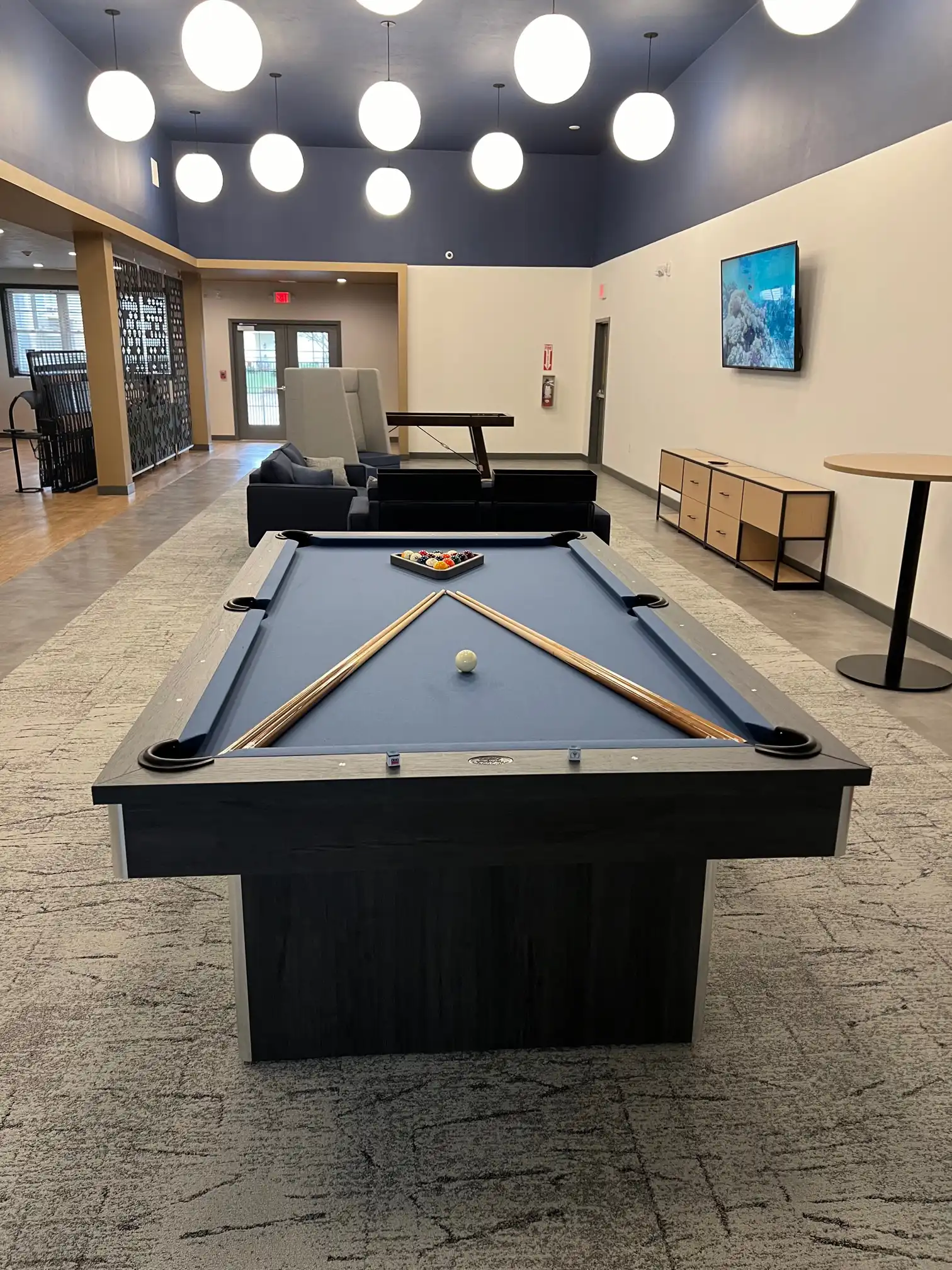 blue Olhausen pool table in a room with white globe lights