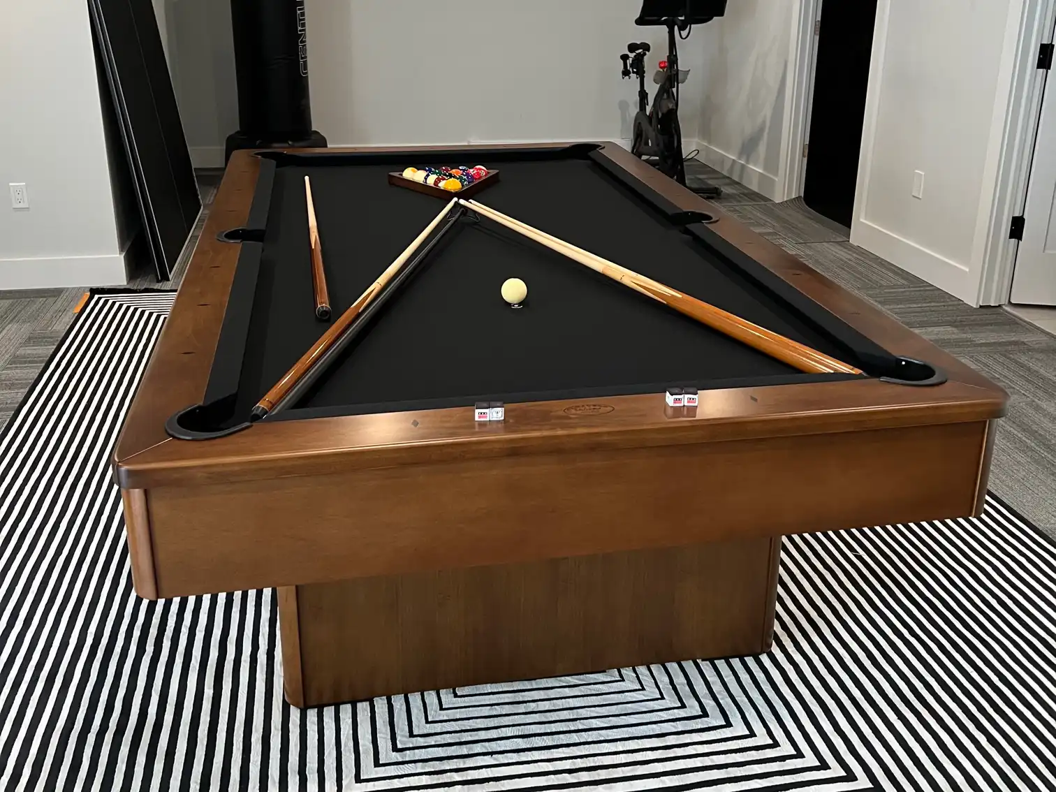 black Olhausen pool table on a black and white striped rug
