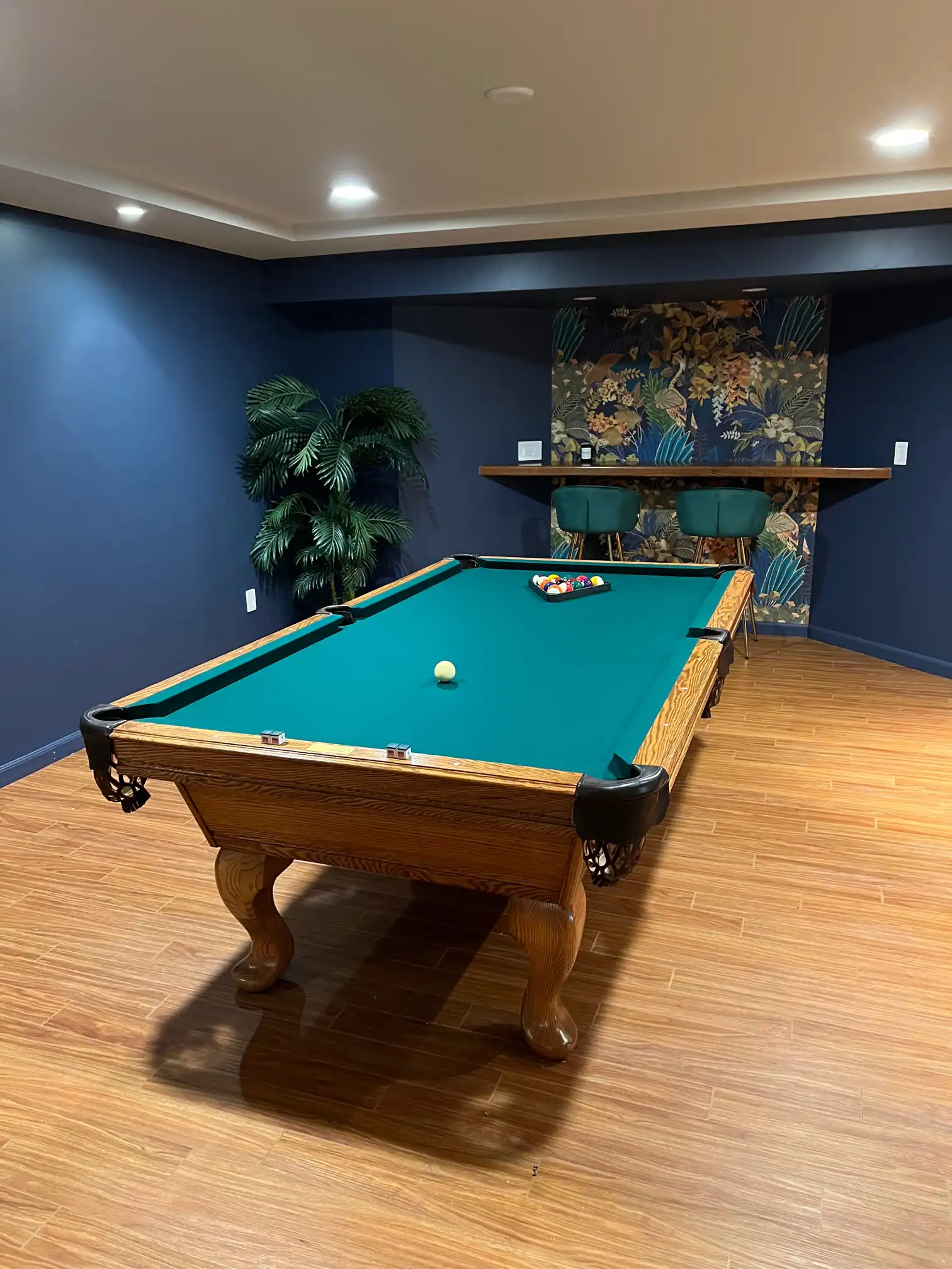 green pool table in a room with blue walls and an oak hardwood floor