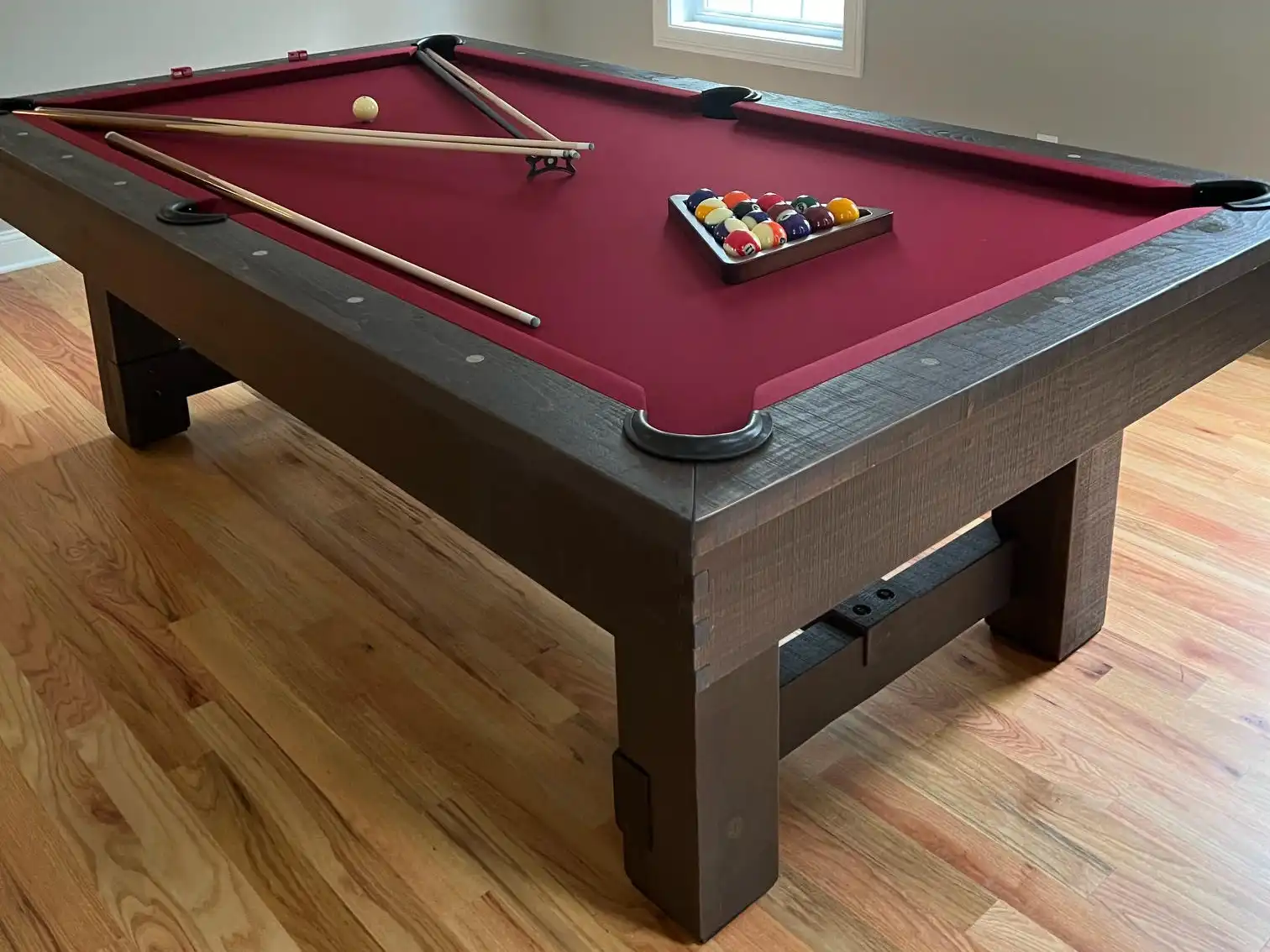 red or maroon felt pool table with dark wood 