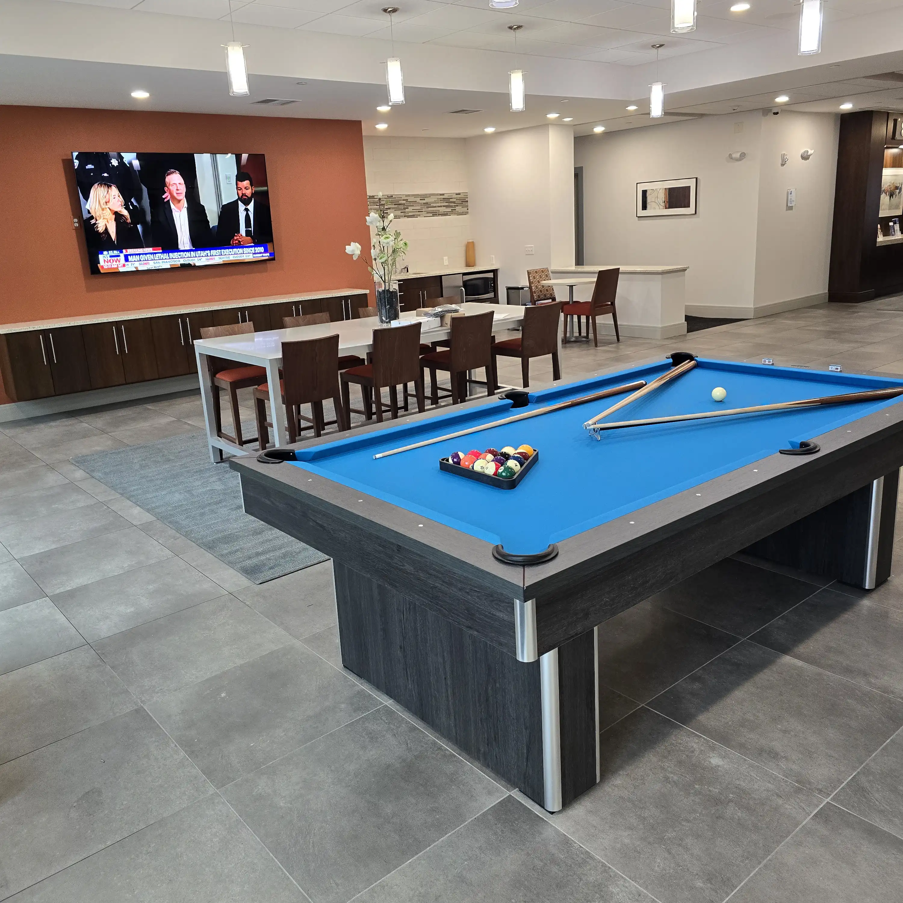 blue pool table with a big screen tv and a dining table in a basement