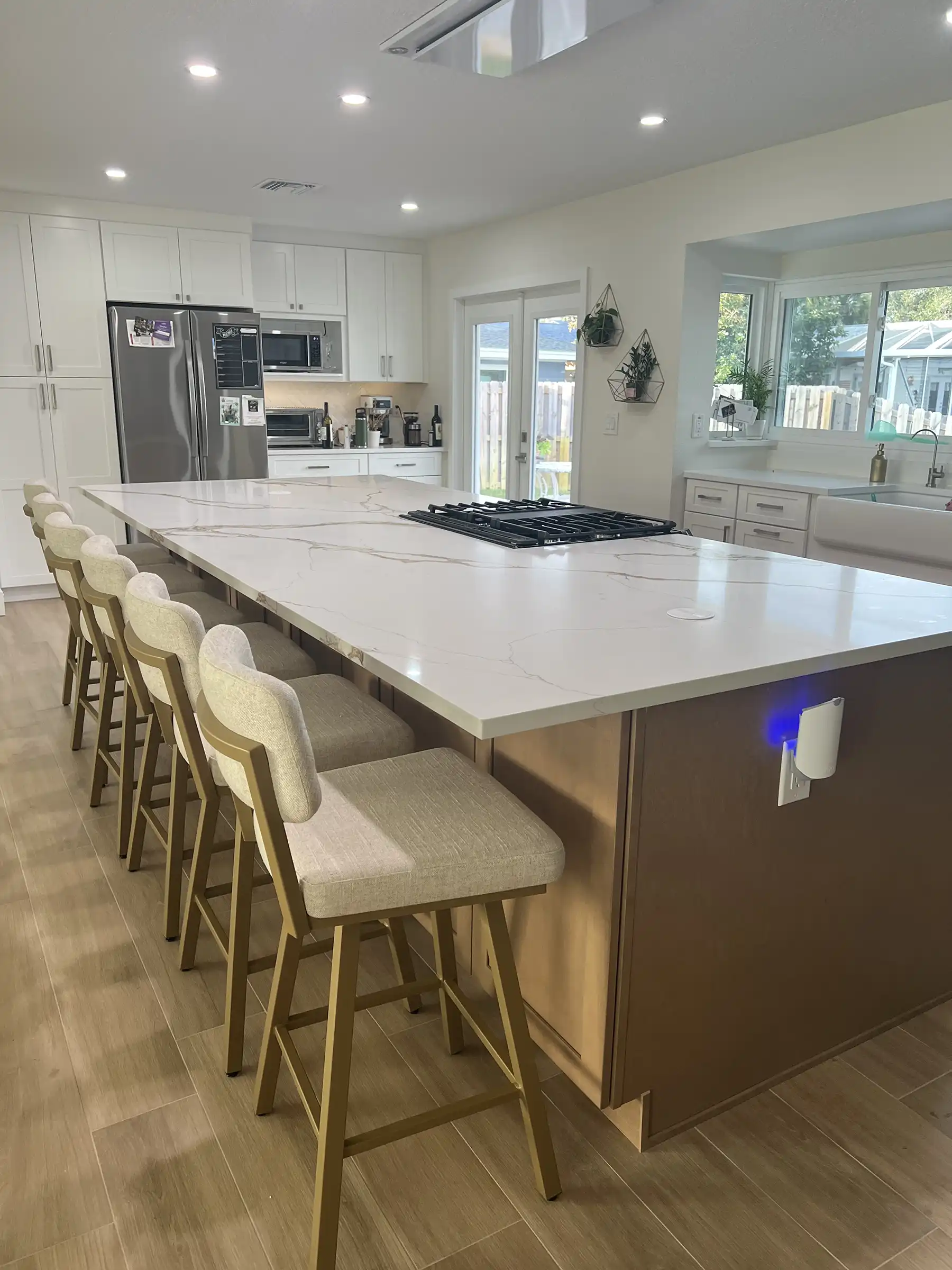 Large kitchen island with seating, quartz countertop, stainless steel appliances, and gas range.